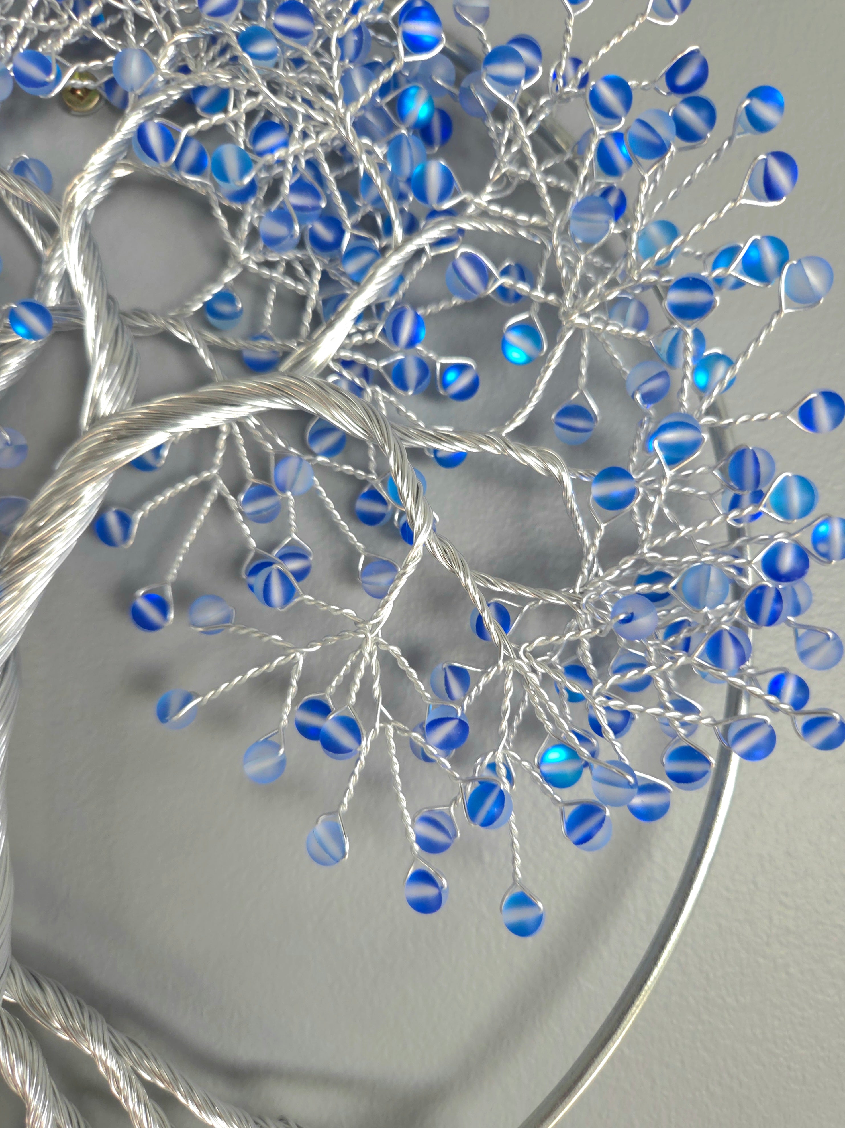 Decorative wall art of a tree with blue beads on a gray background