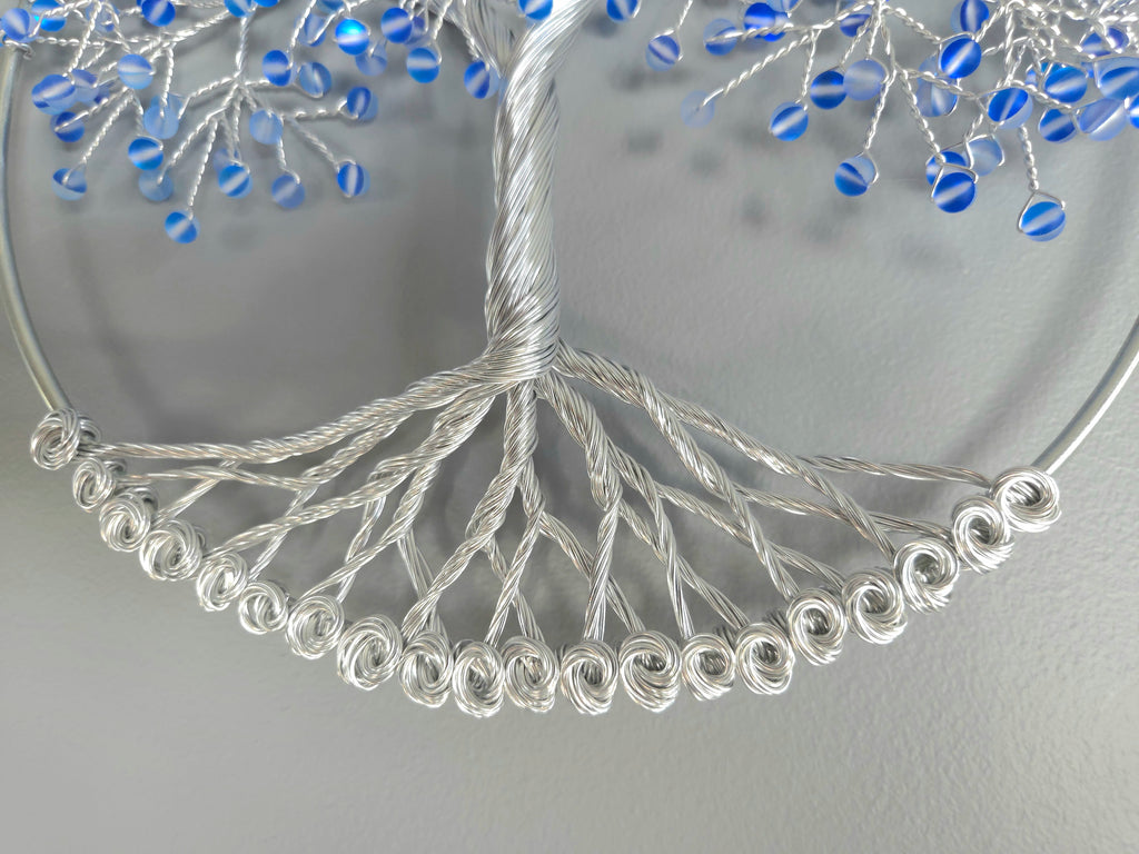 Decorative wall art of a tree with blue beads on a gray background