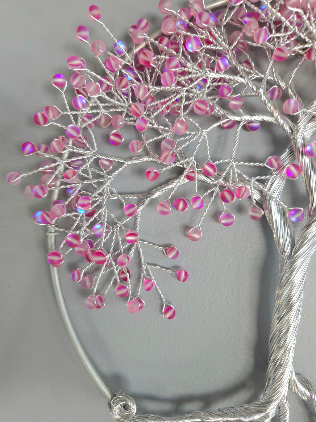 Decorative wall art of a tree with pink beads on a gray background