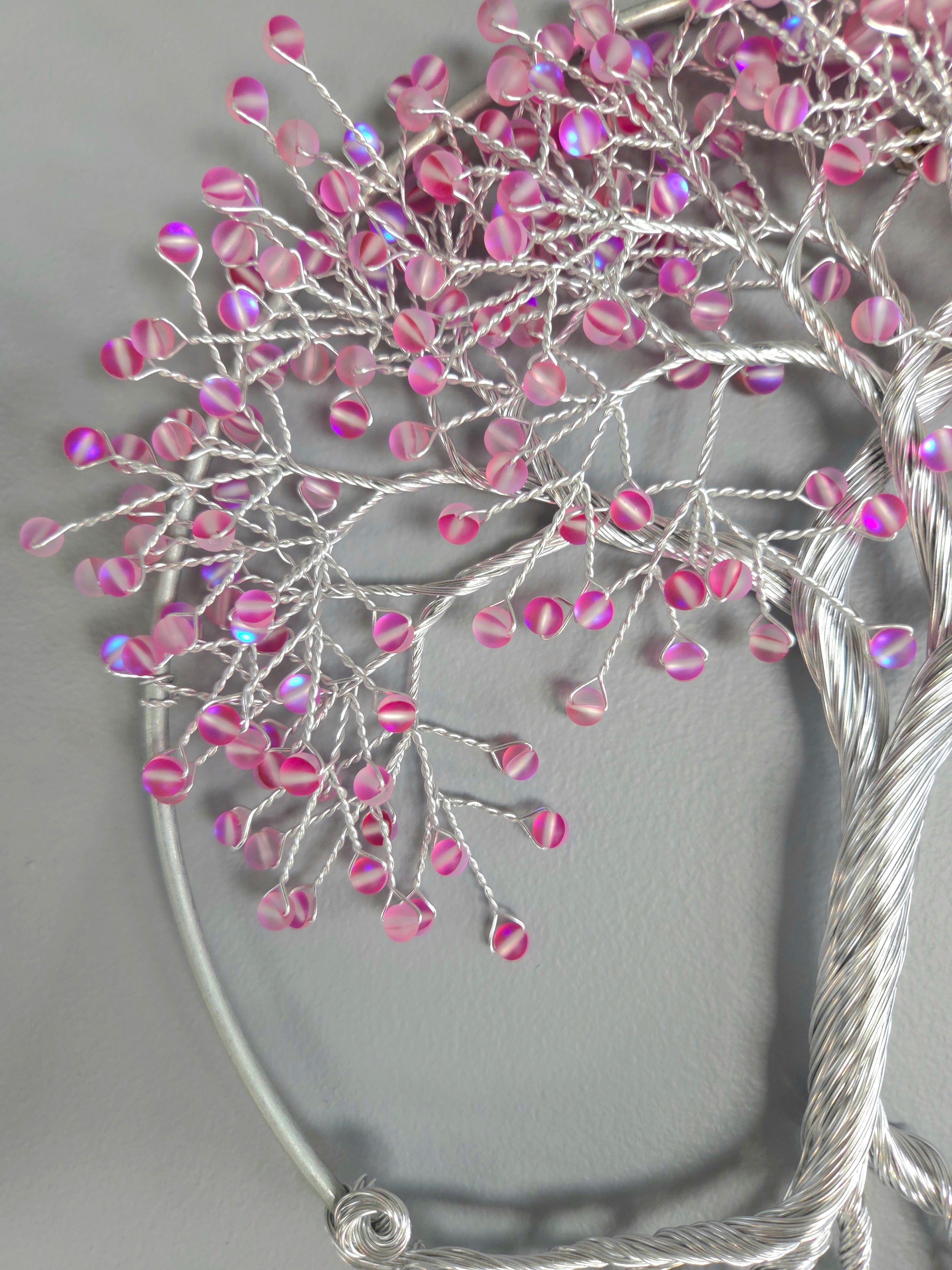Decorative wall art of a tree with pink beads on a gray background