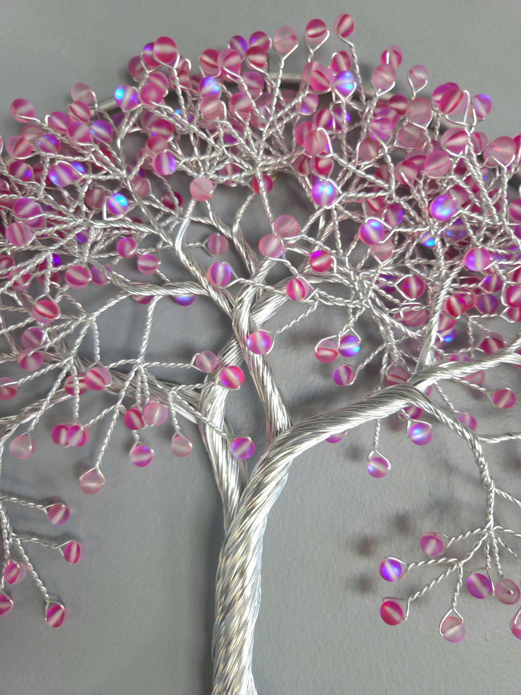 Decorative wall art of a tree with pink beads on a gray background