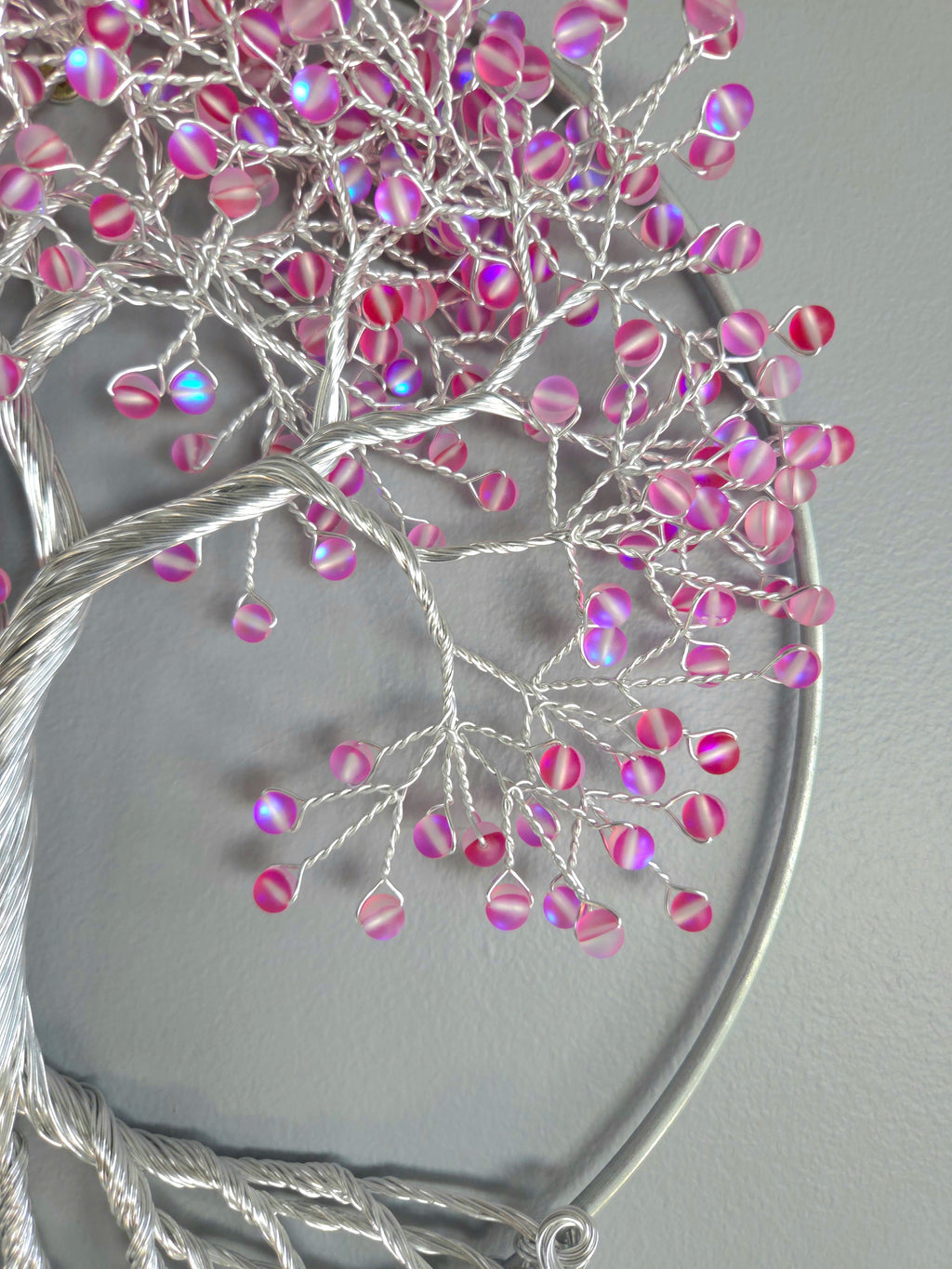 Decorative wall art of a tree with pink beads on a gray background
