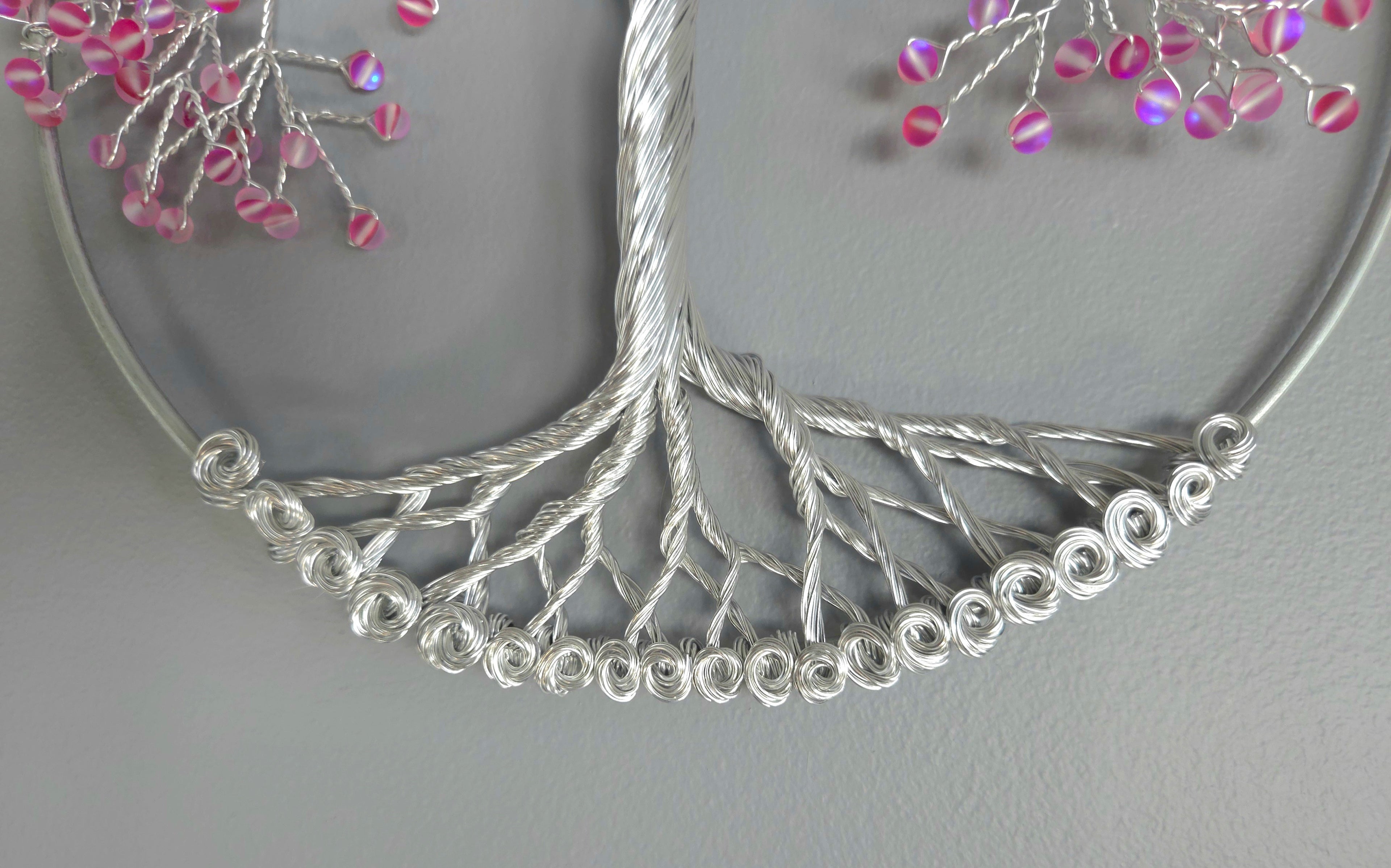 Decorative wall art of a tree with pink beads on a gray background