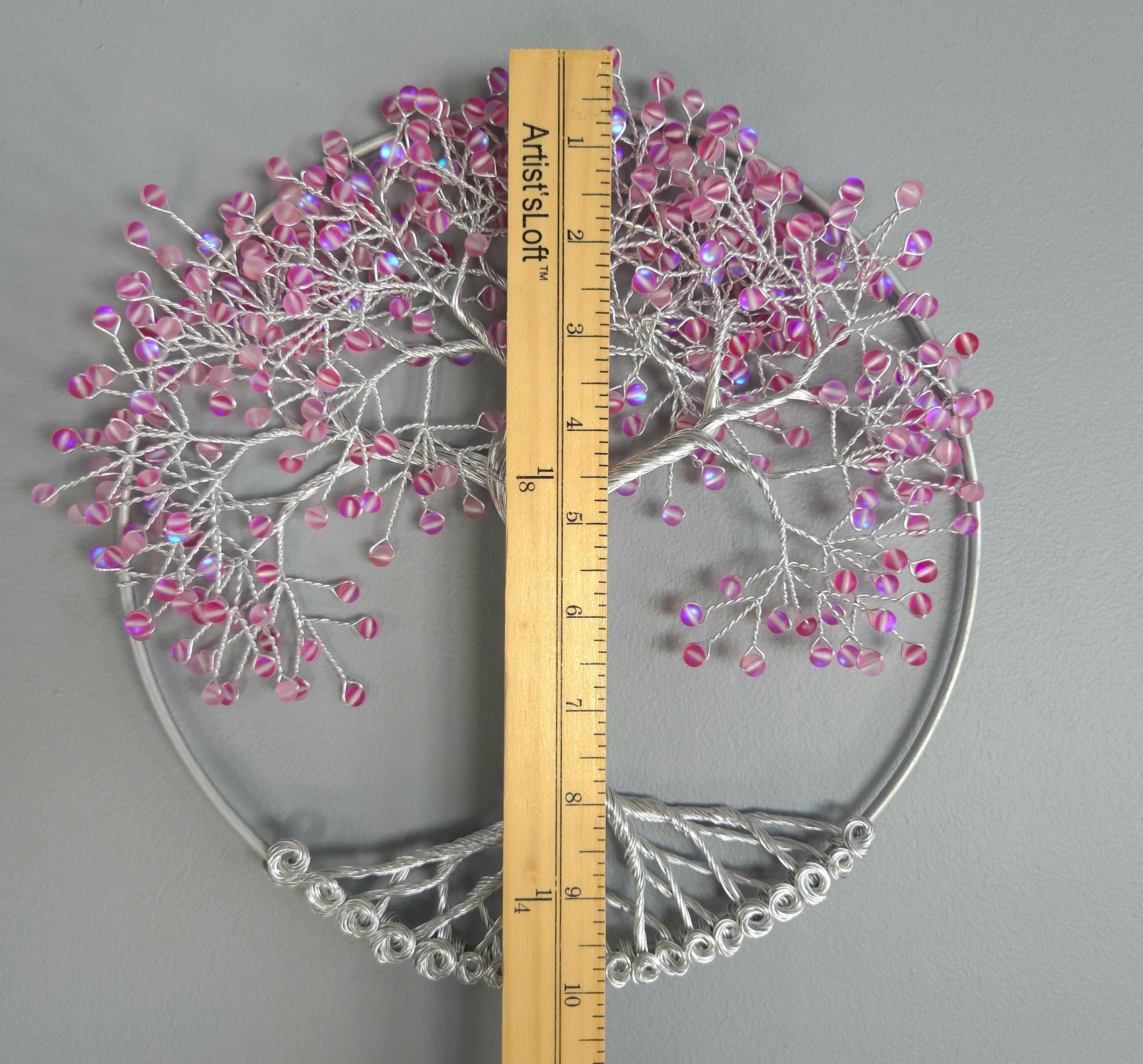 Decorative wall art of a tree with pink beads on a gray background