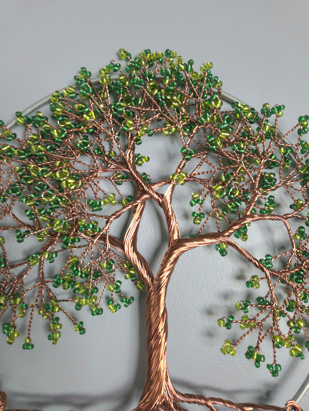 Decorative wall art of a tree with green beads on a gray background