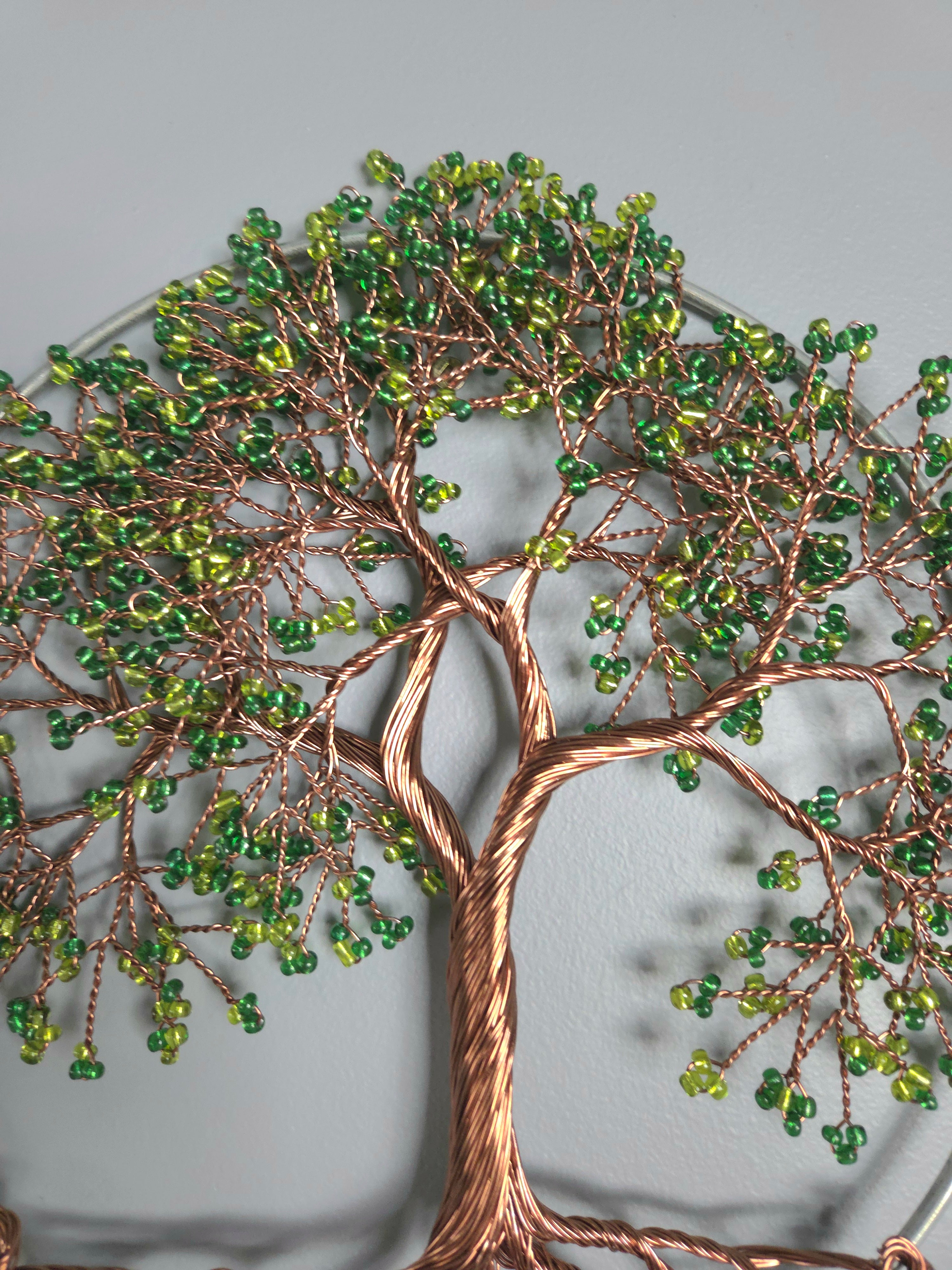 Decorative wall art of a tree with green beads on a gray background