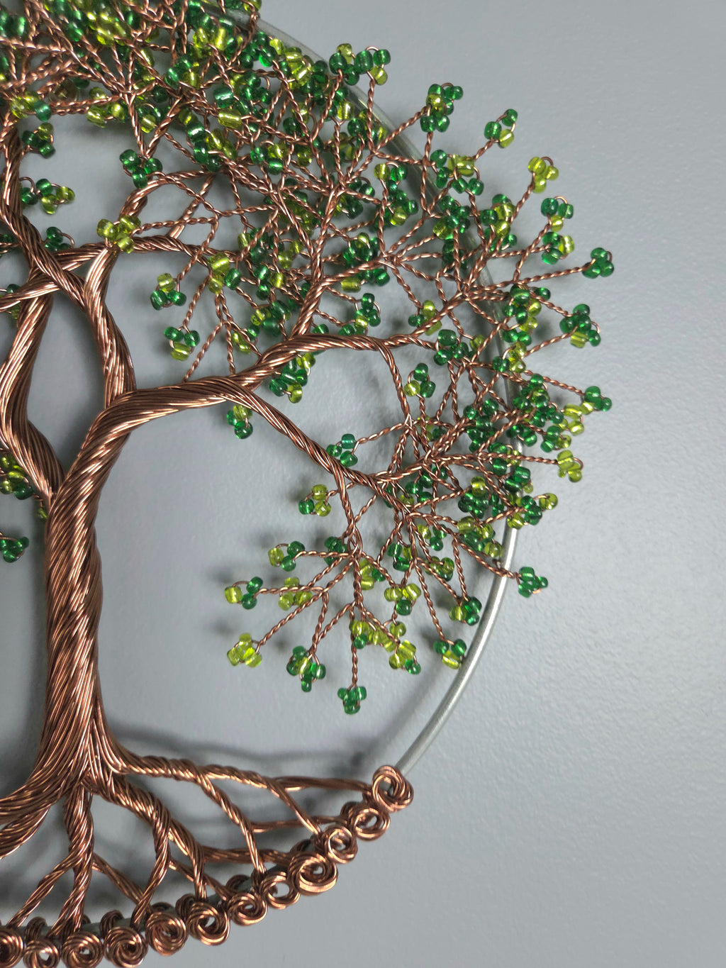 Decorative wall art with a tree design featuring green beads on a gray background