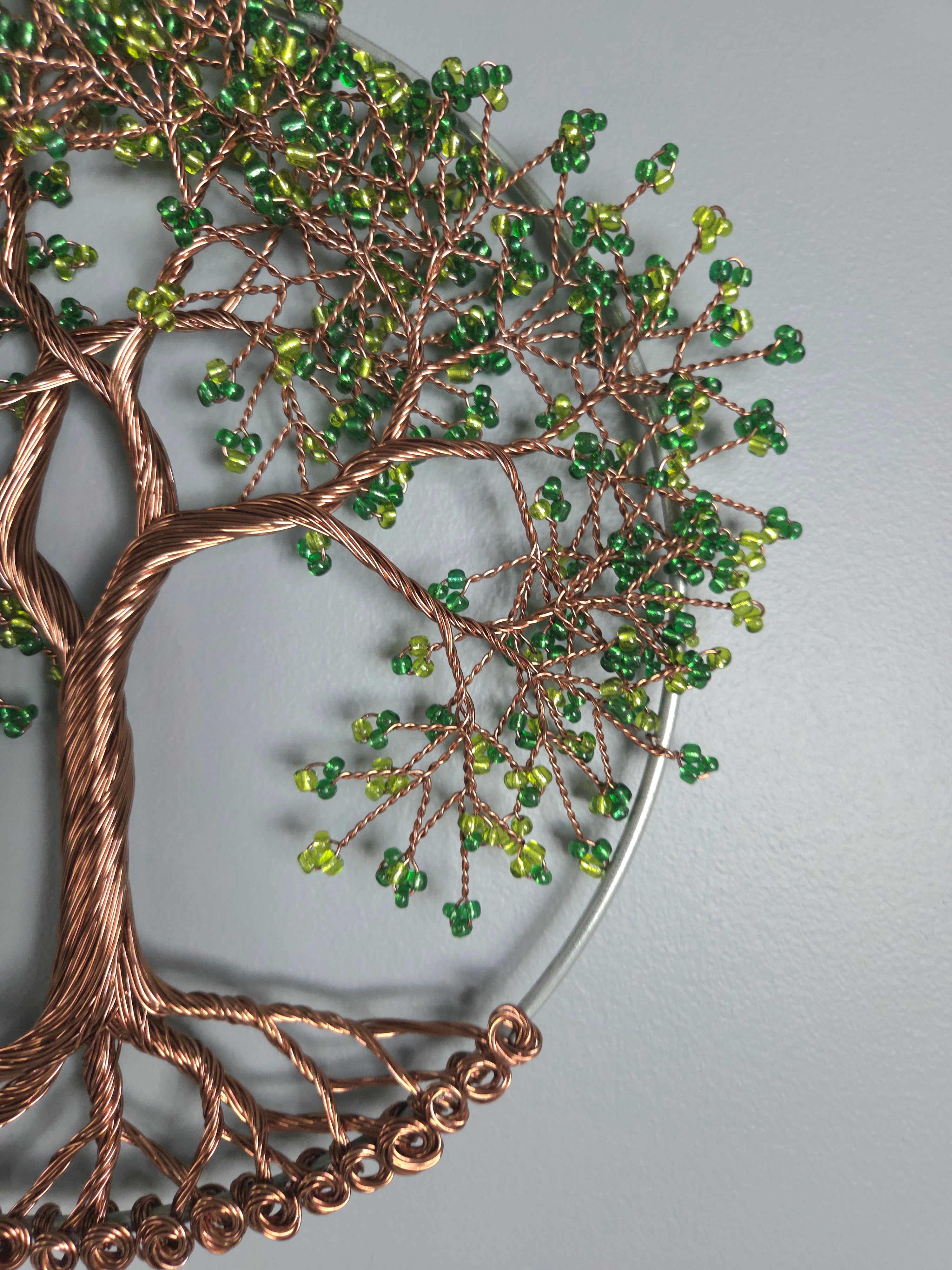 Decorative wall art with a tree design featuring green beads on a gray background