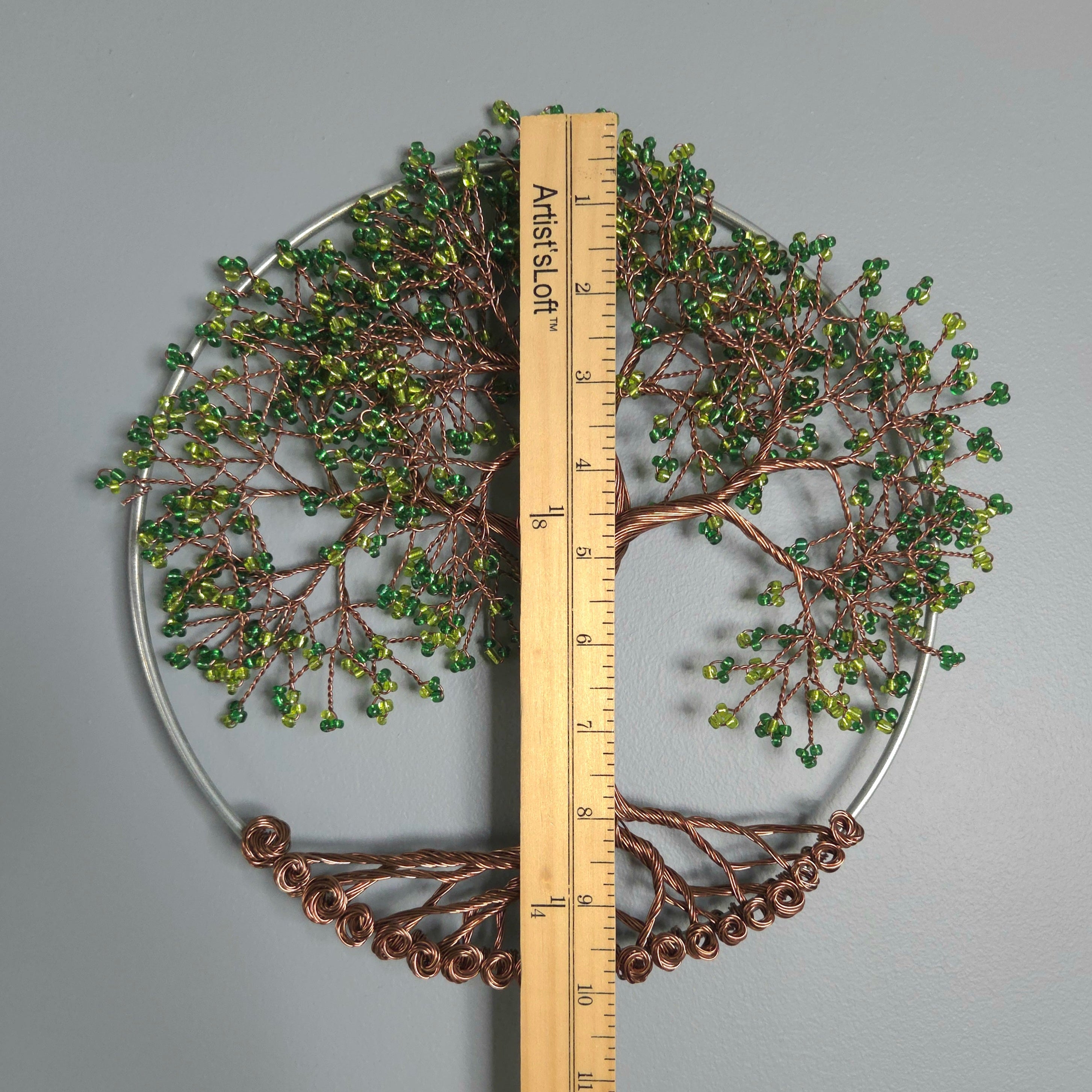 Decorative wall art with a tree design and a ruler for scale on a gray background