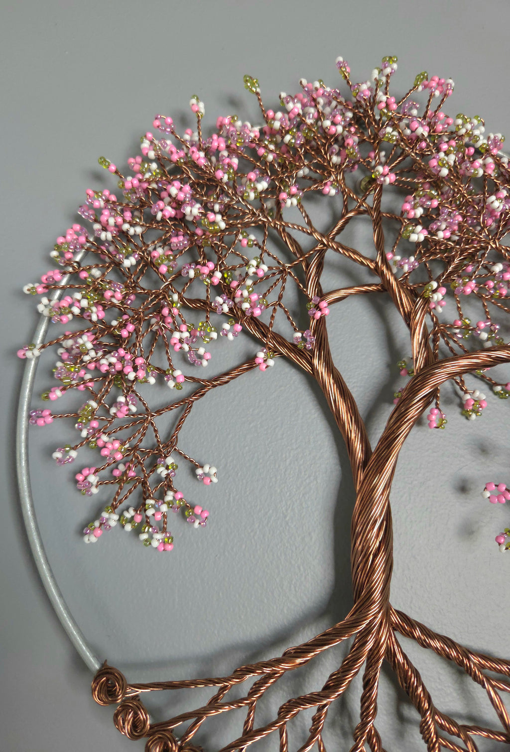 Decorative wall art of a tree with pink blossoms on a gray background