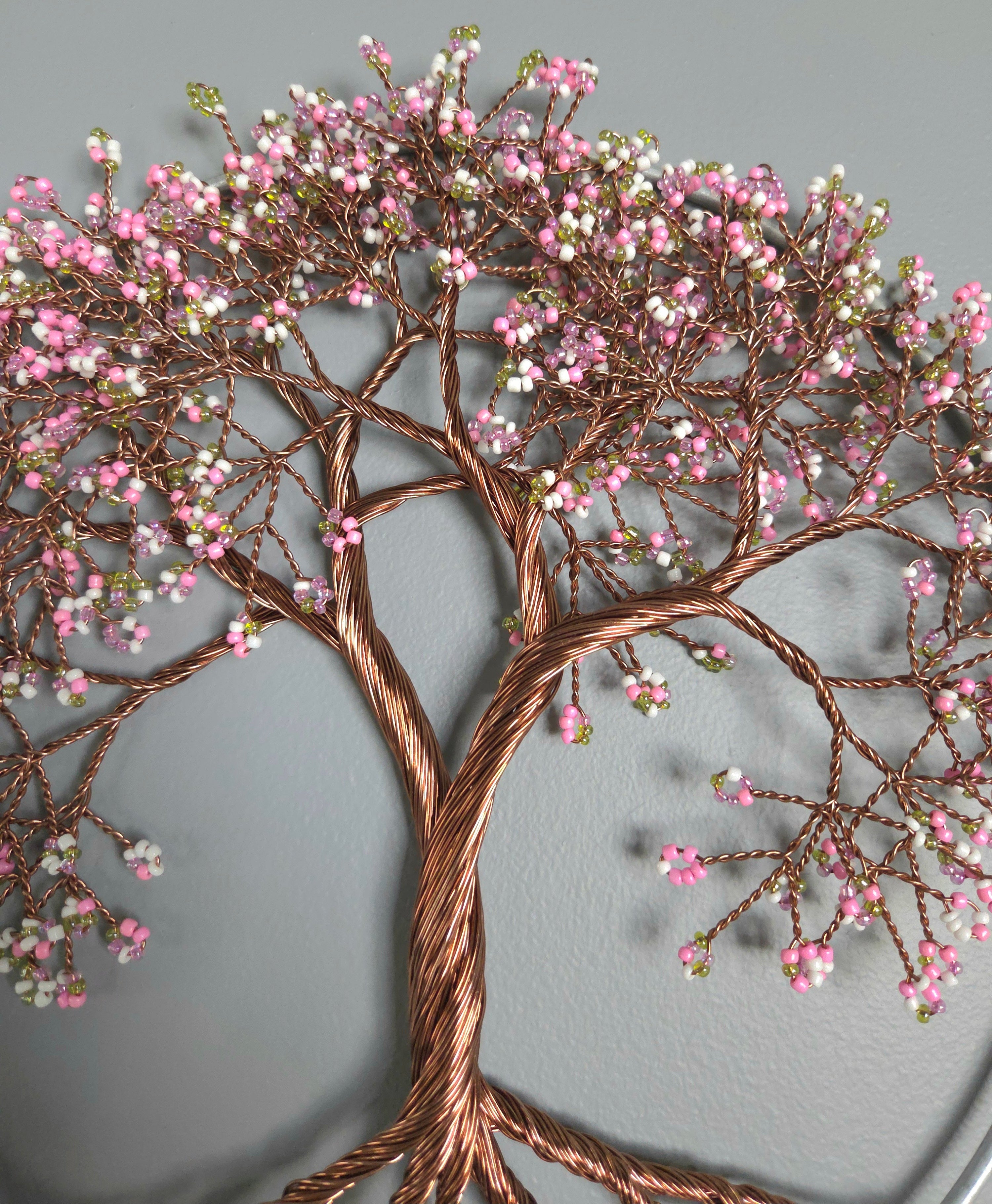 Decorative wall art of a tree with pink blossoms on a gray background