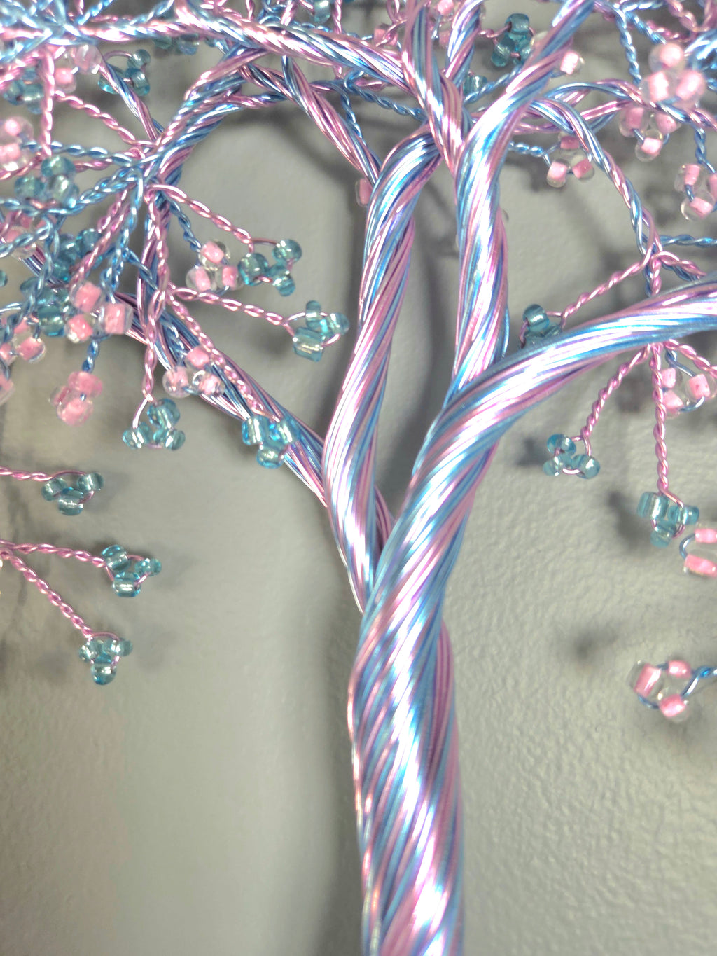 Decorative tree wall art with pink and blue branches on a gray background