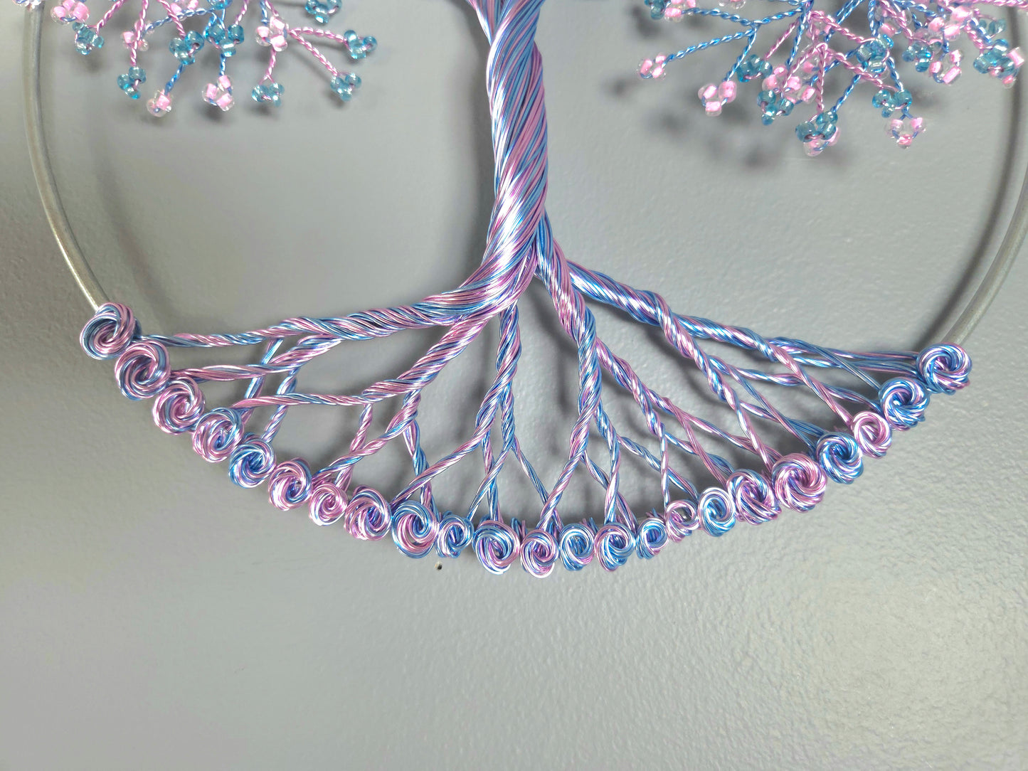 Decorative tree wall art with pink and blue branches on a gray background