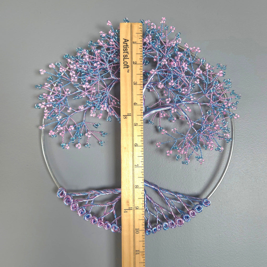 Decorative tree wall art with pink and blue branches on a gray background