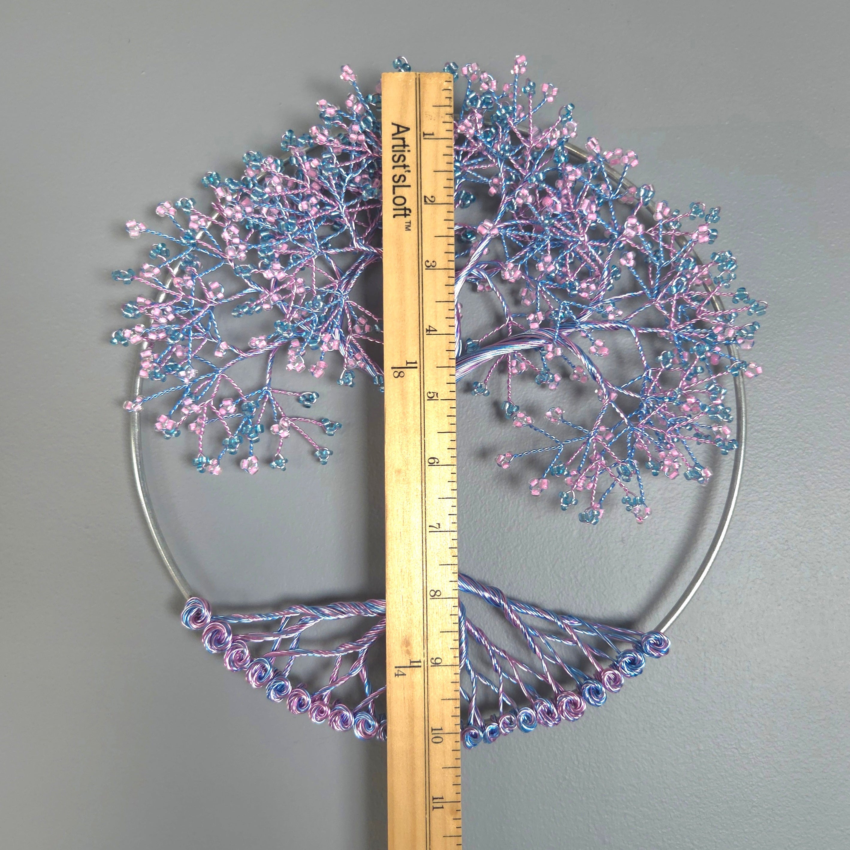 Decorative tree wall art with pink and blue branches on a gray background