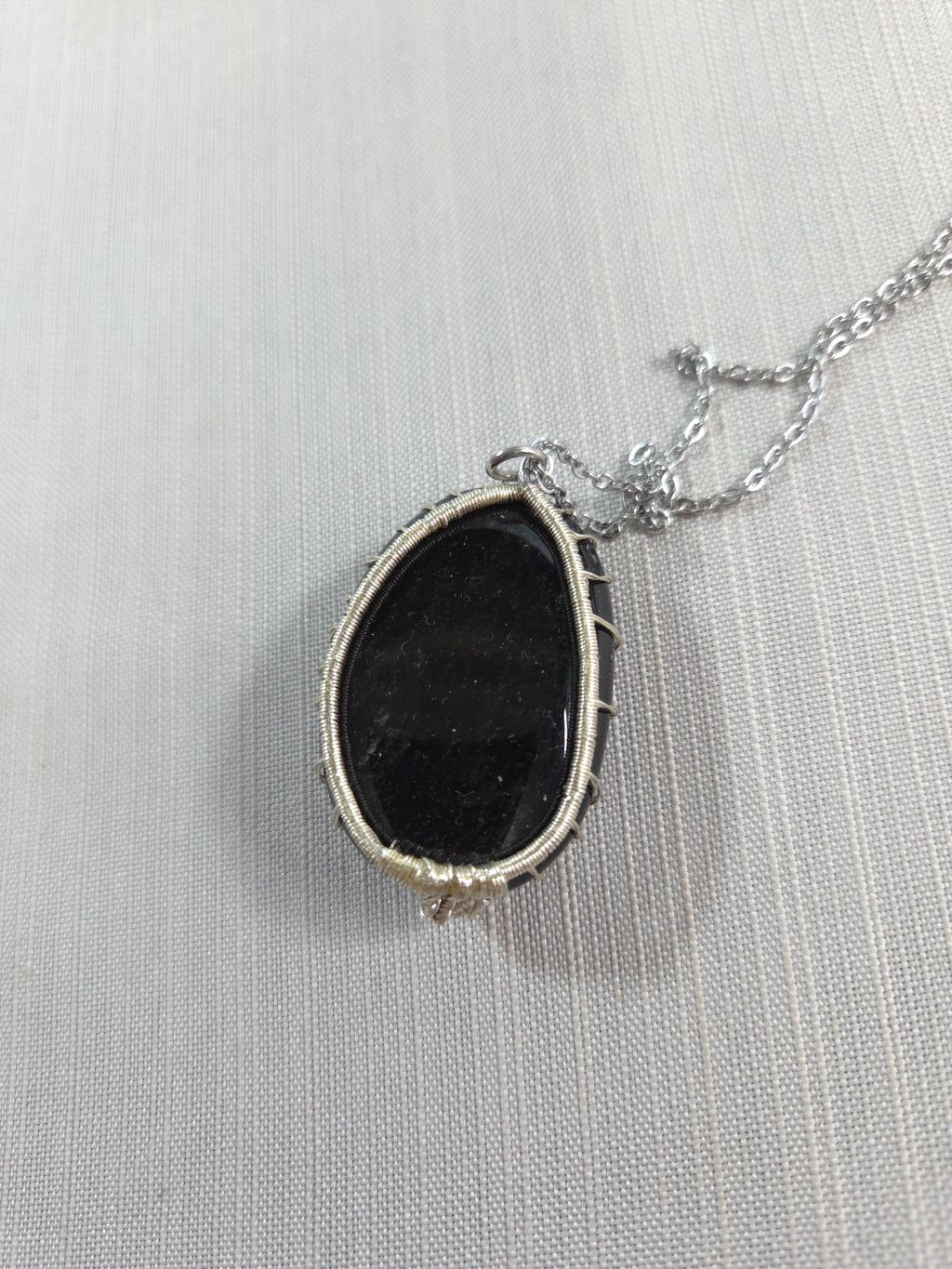 Necklace with a black stone pendant on a light gray background