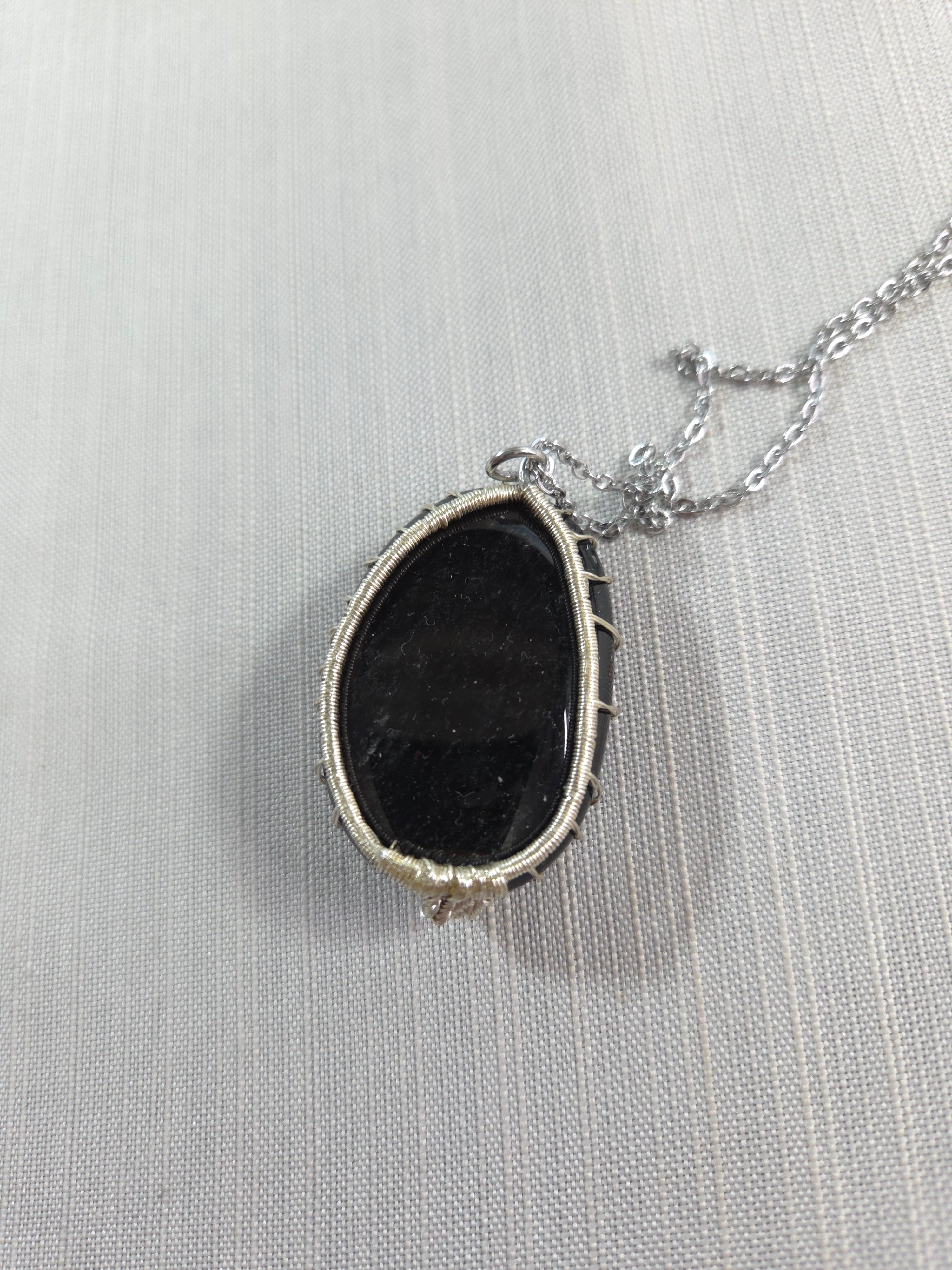 Necklace with a black stone pendant on a light gray background