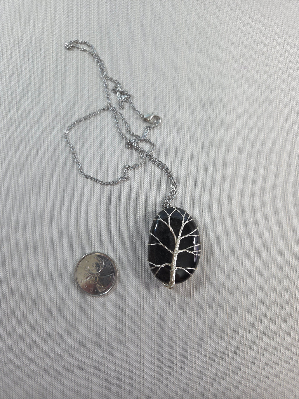 Black and silver pendant with chain on a light gray background
