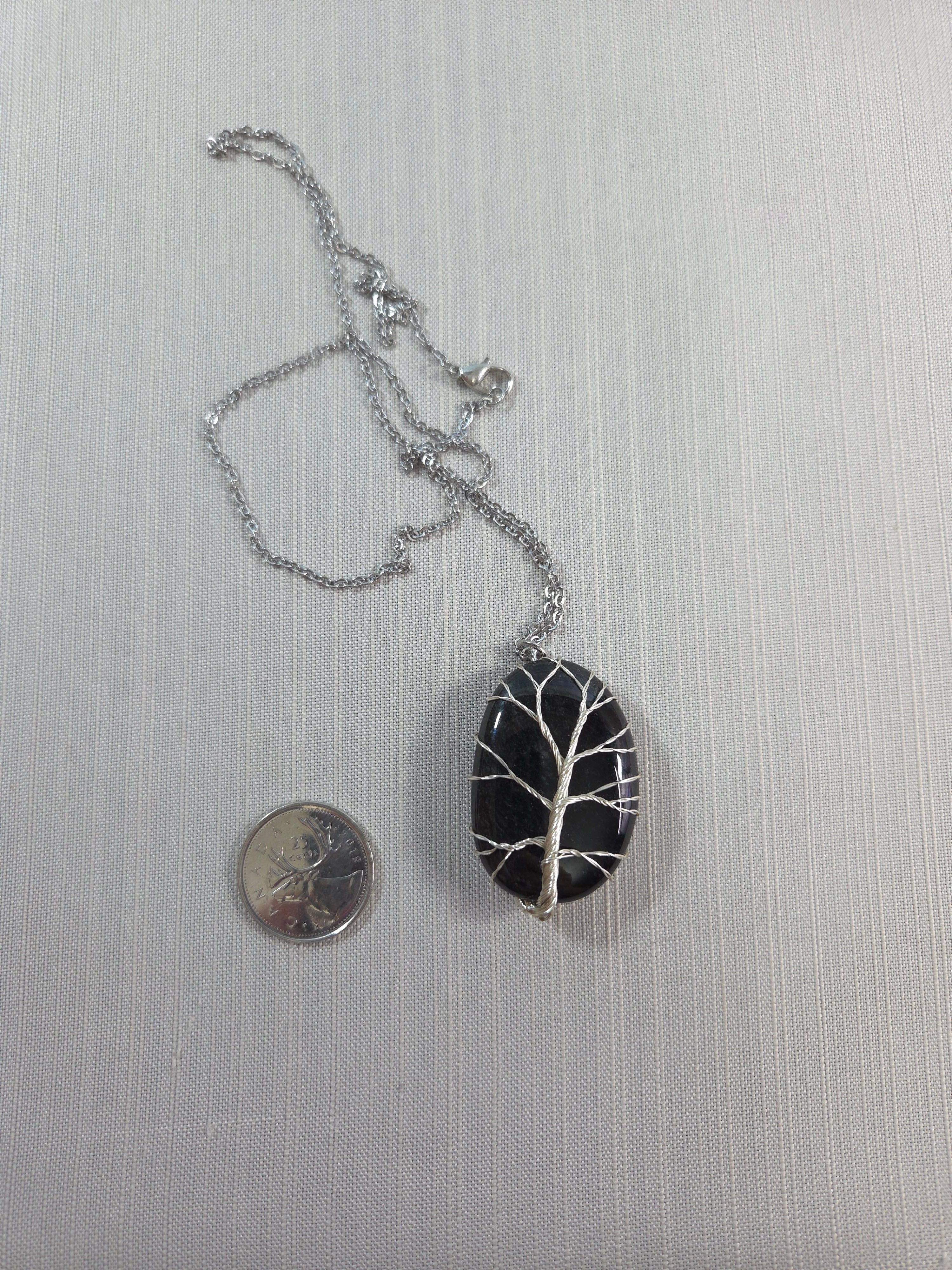 Black and silver pendant with chain on a light gray background