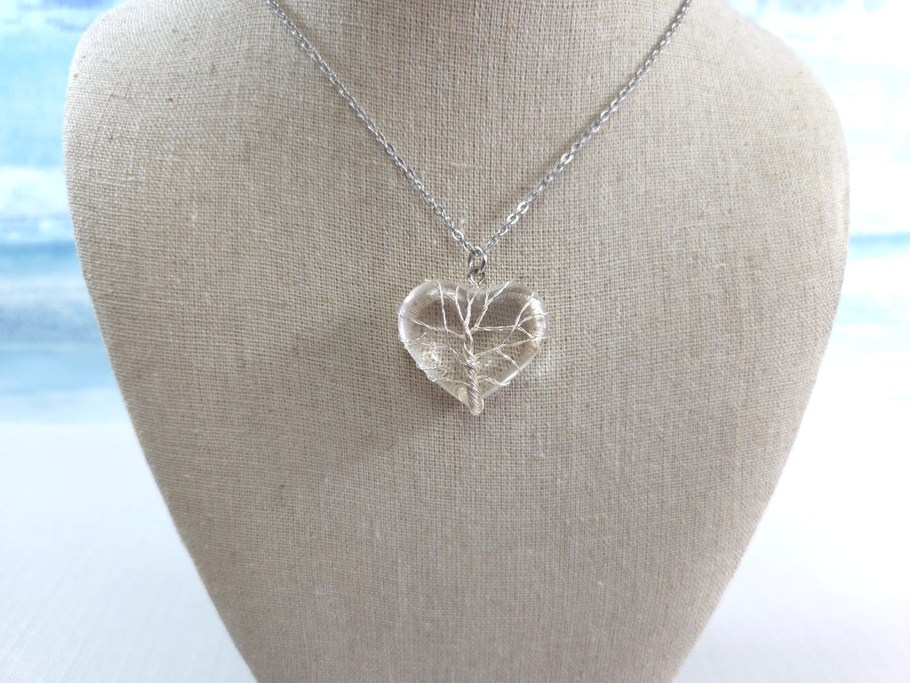 Silver heart-shaped pendant necklace on a mannequin bust with a blurred natural background
