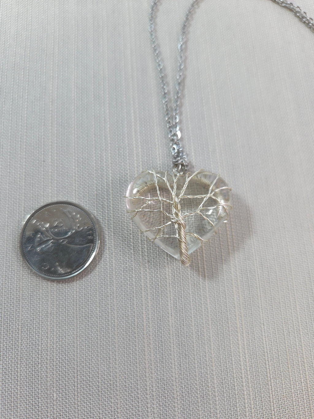 Crystal pendant necklace on a light gray background with a quarter for scale.