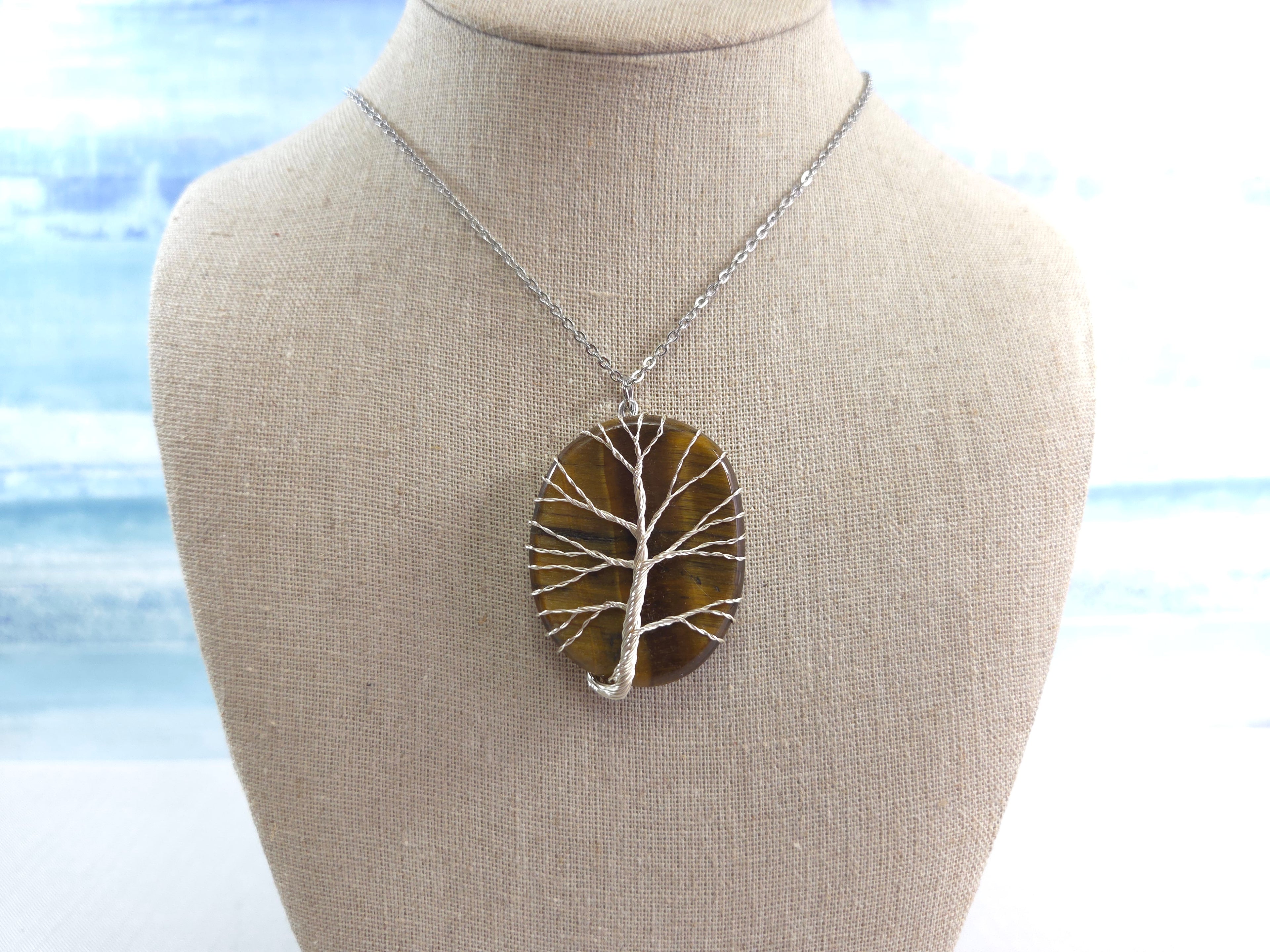 necklace with a tree-of-life pendant against a blurred natural background