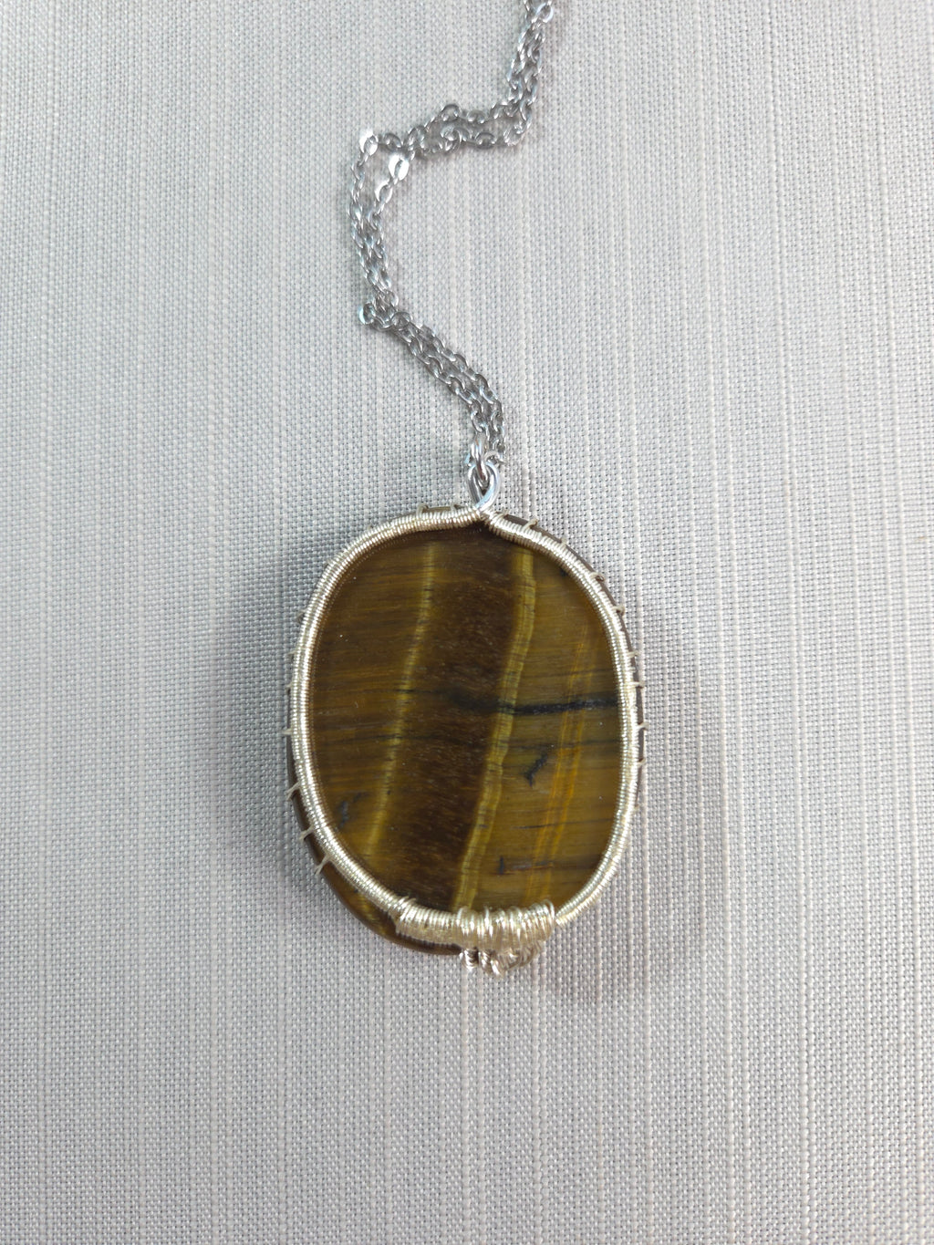 Necklace with a tiger's eye stone on a light gray background