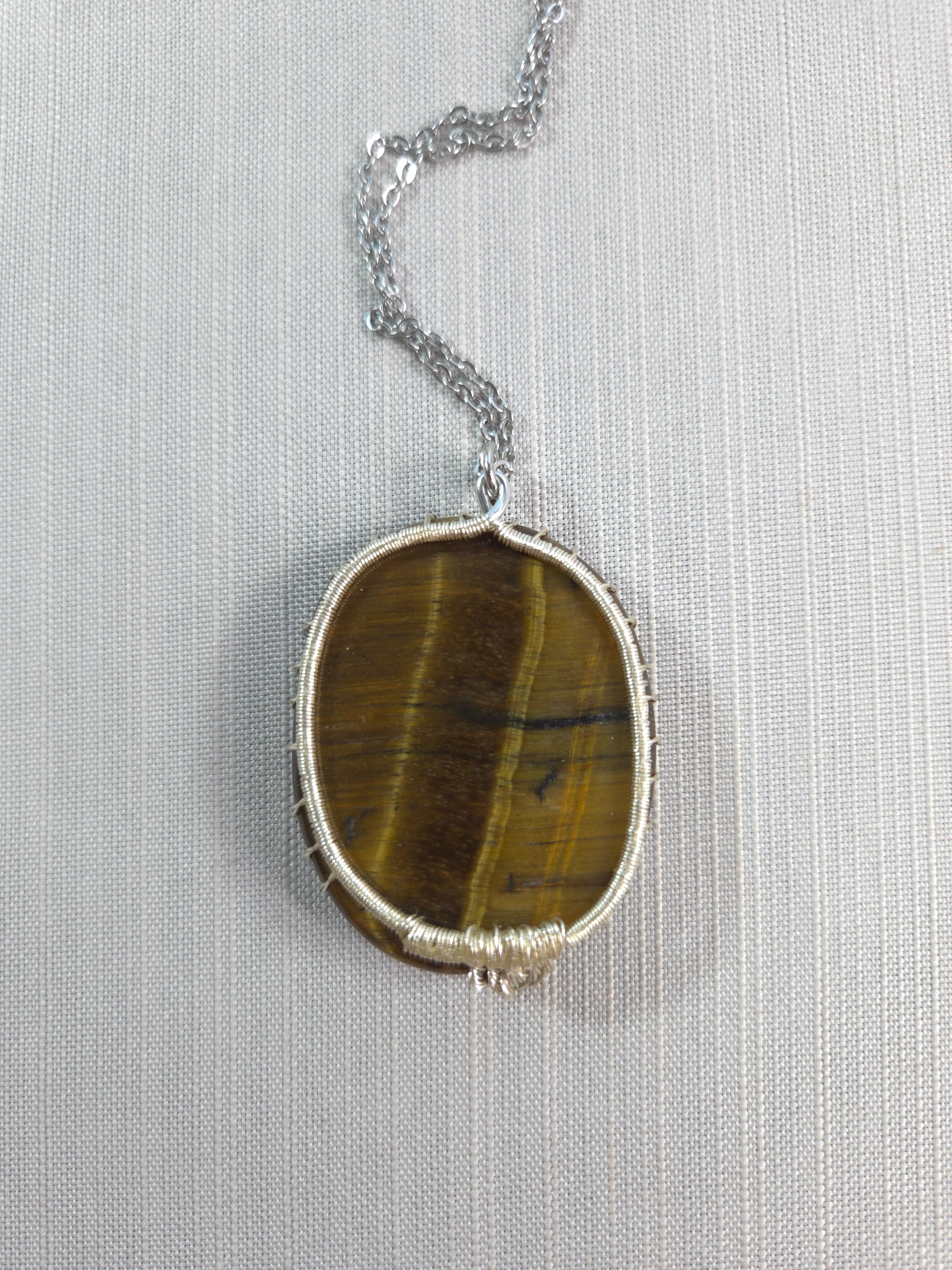 Necklace with a tiger's eye stone on a light gray background