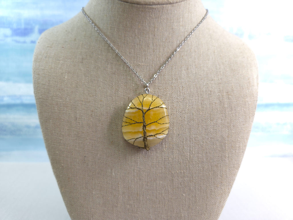Necklace with a yellow stone pendant on a mannequin bust against a blurred natural background