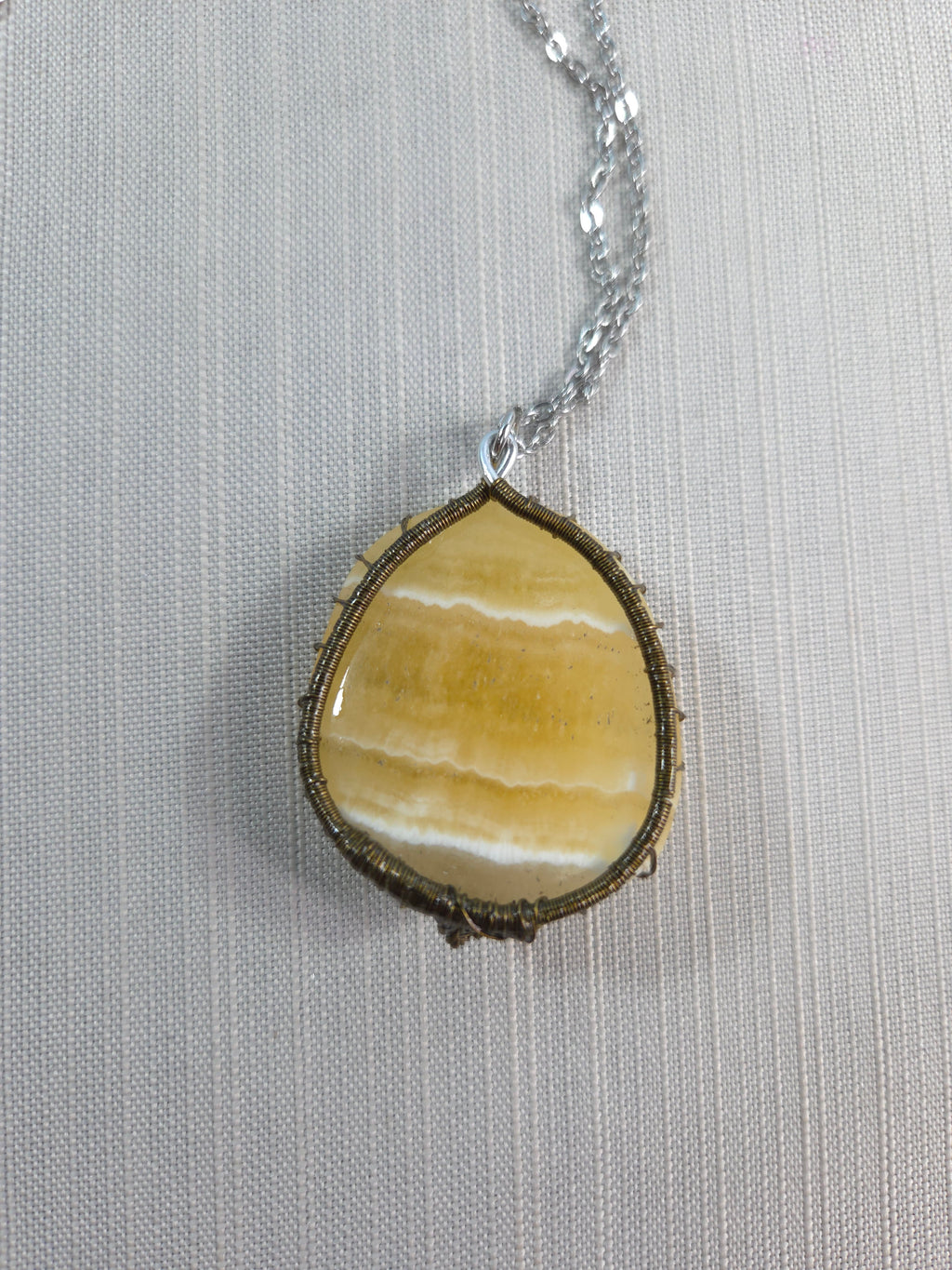 Necklace with a yellow stone pendant on a light gray background