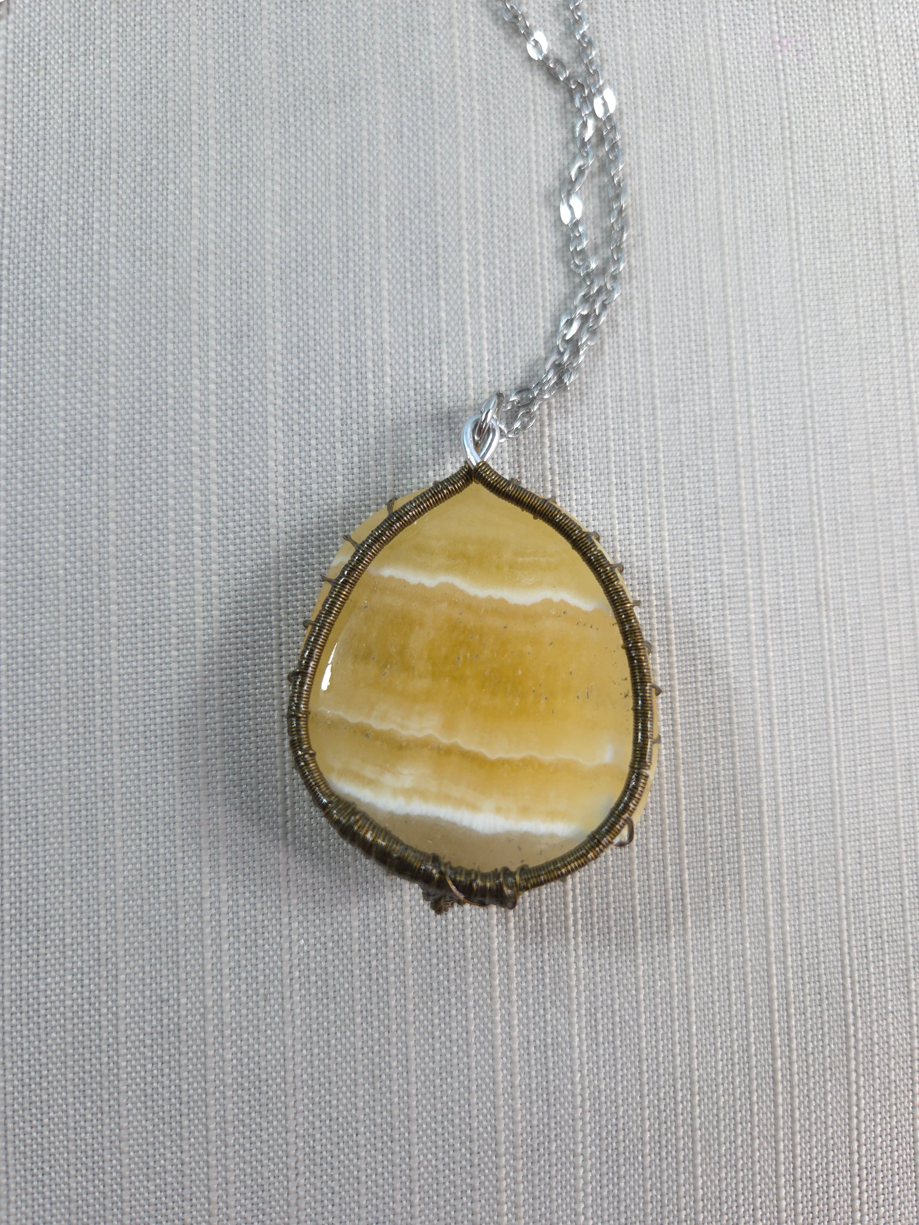 Necklace with a yellow stone pendant on a light gray background