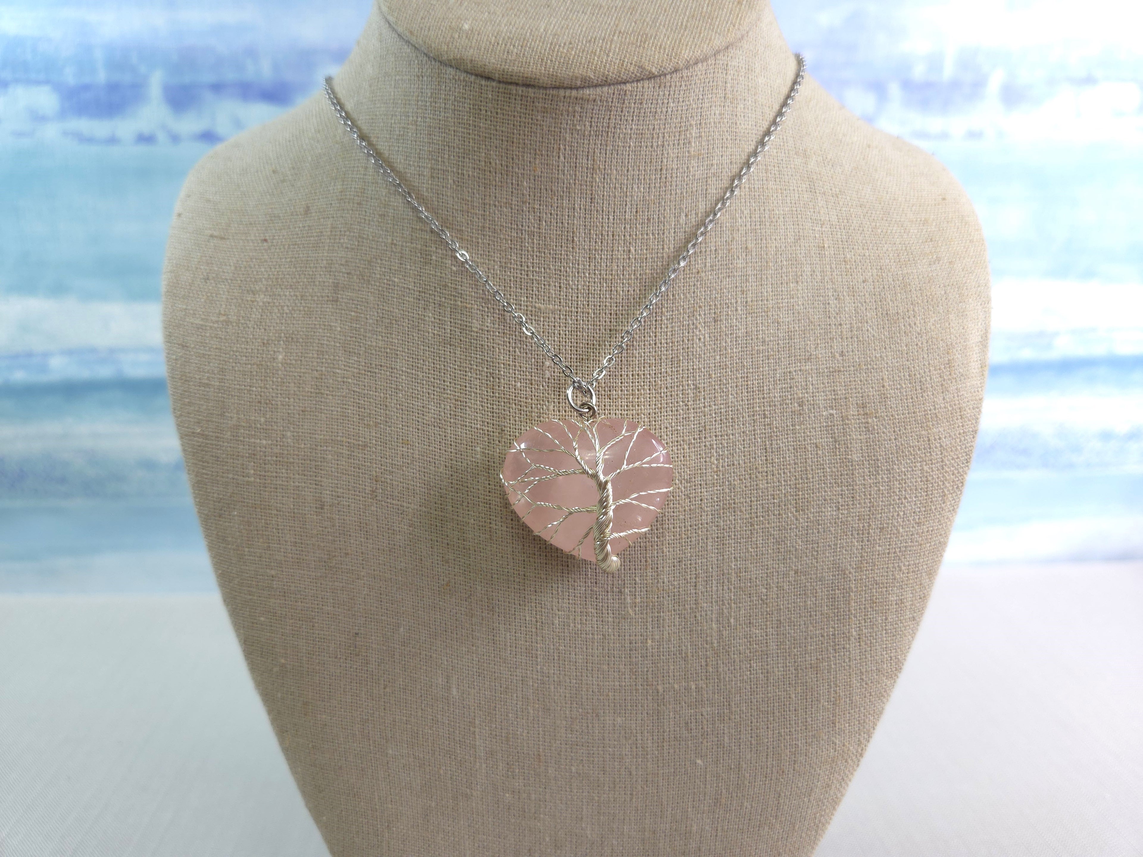 Necklace with a pink pendant on a mannequin bust against a beach background