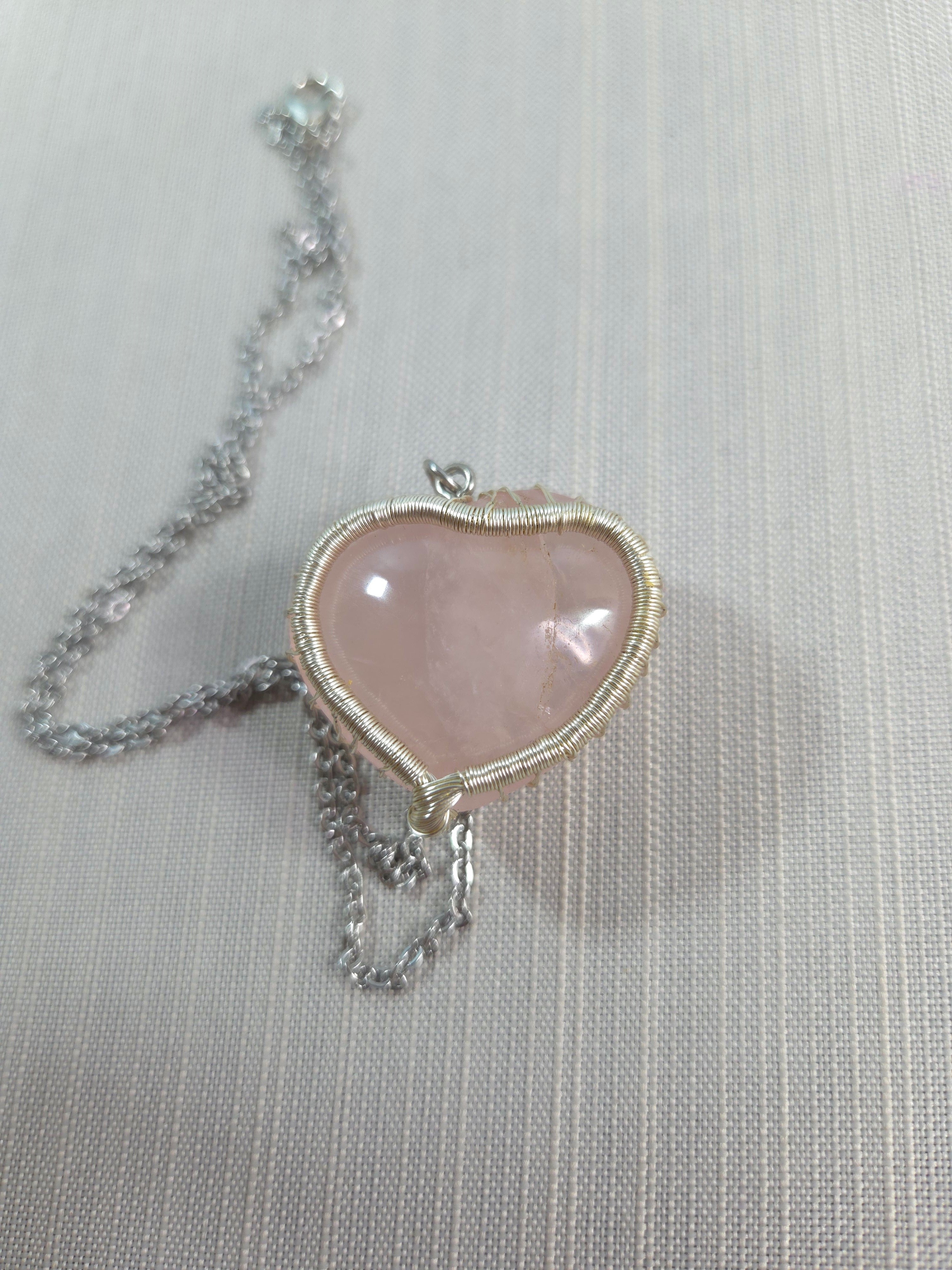 Necklace with a pink heart-shaped pendant on a light gray background