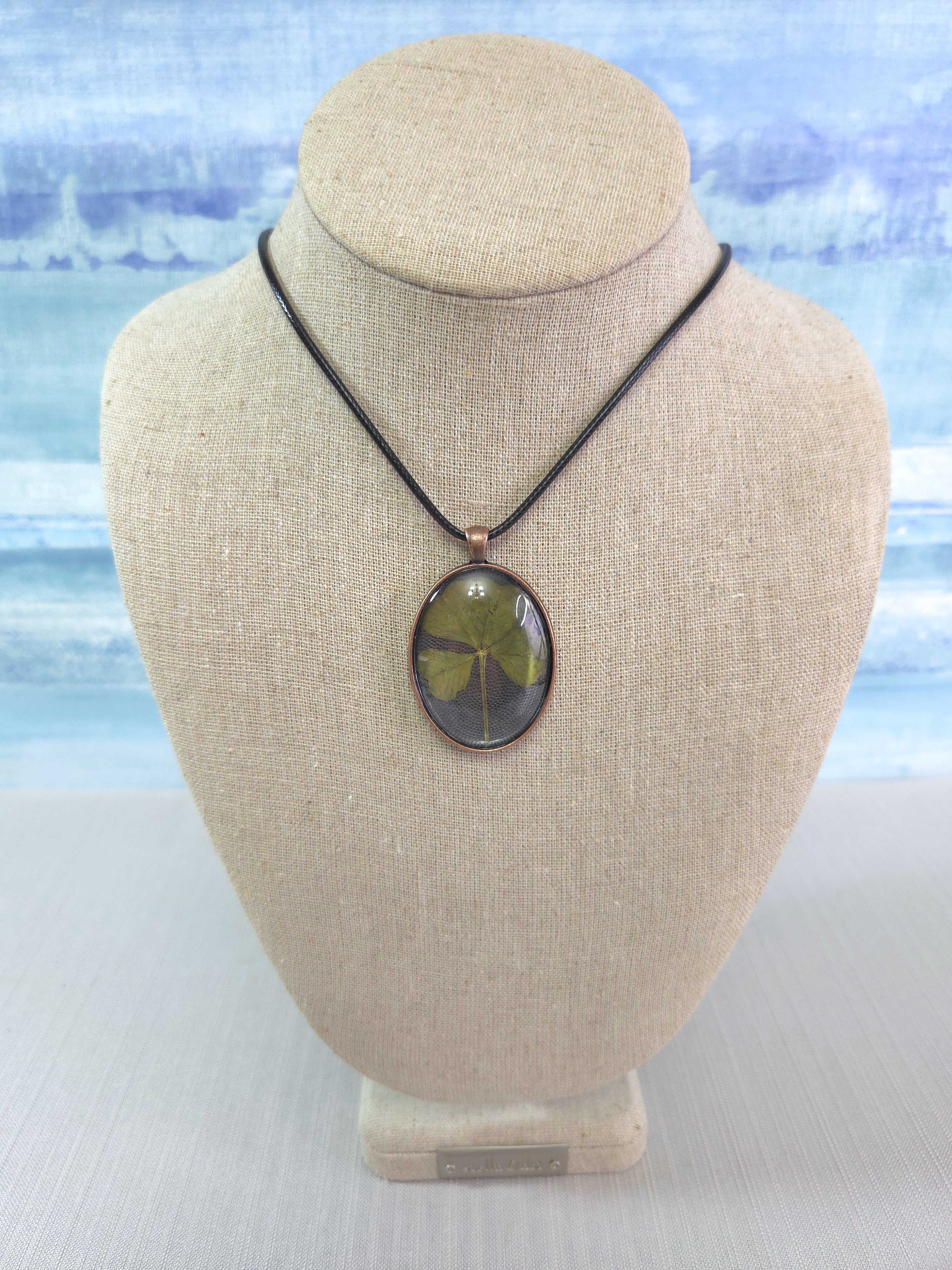 Necklace with a pendant on a beige bust against a light blue and white striped background