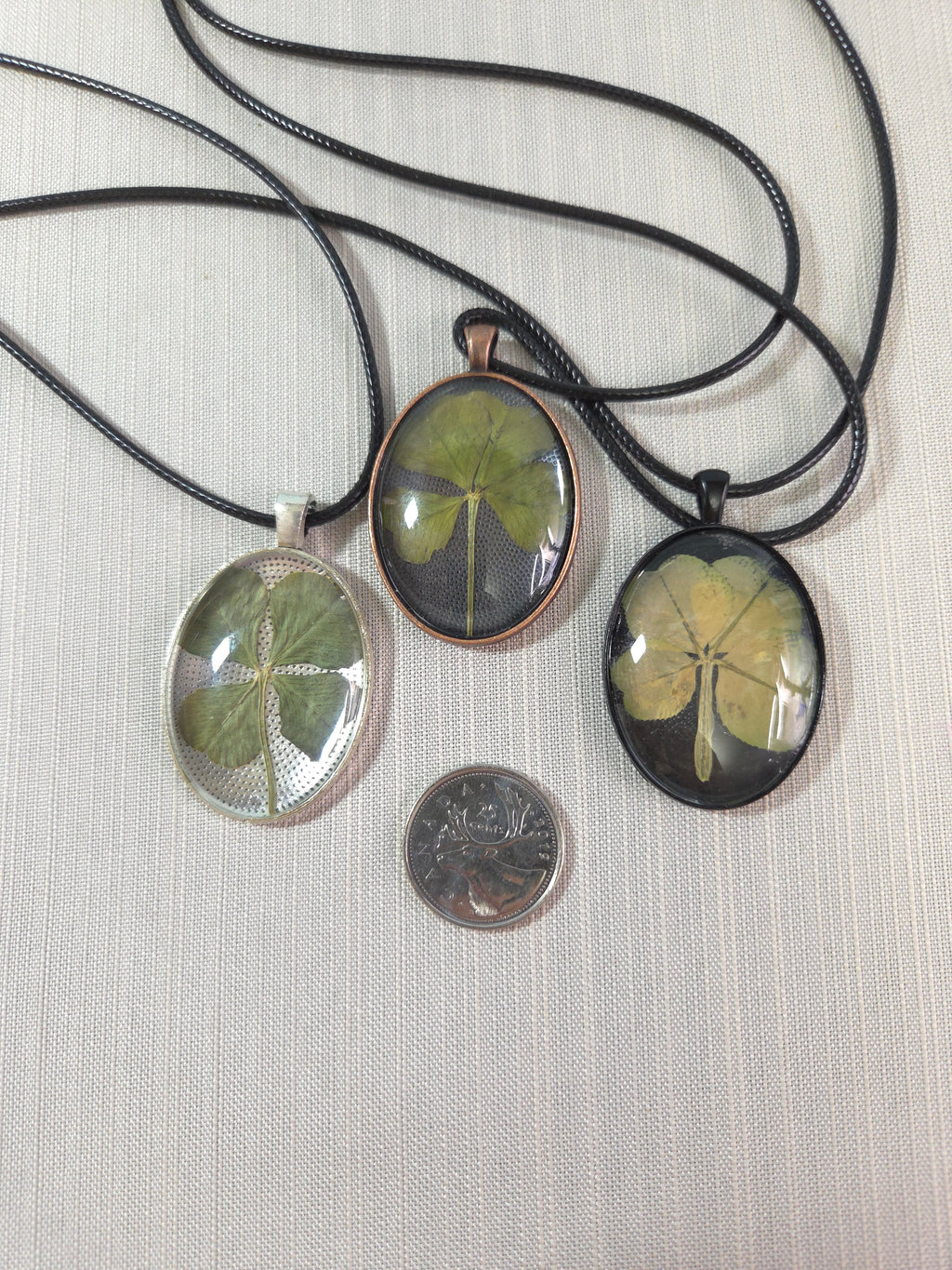 Three pendants with leaf designs on a textured surface