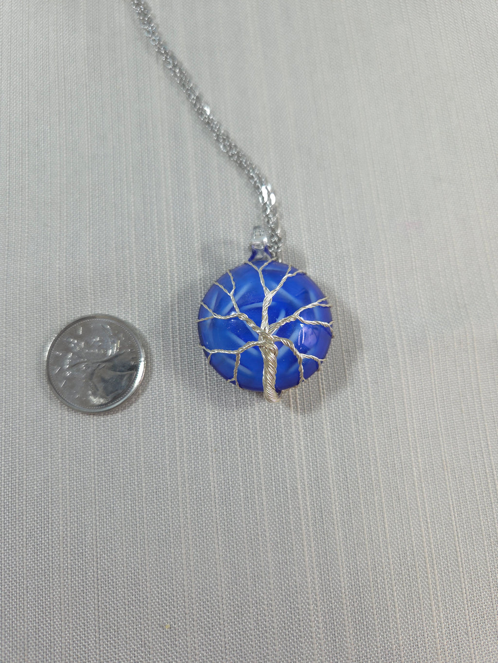 Blue pendant necklace with silver chain on a gray background