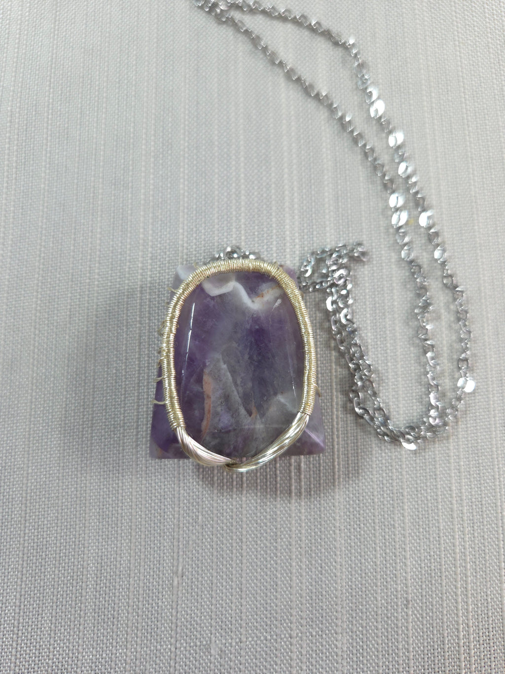 Necklace with a purple pendant on a light gray background