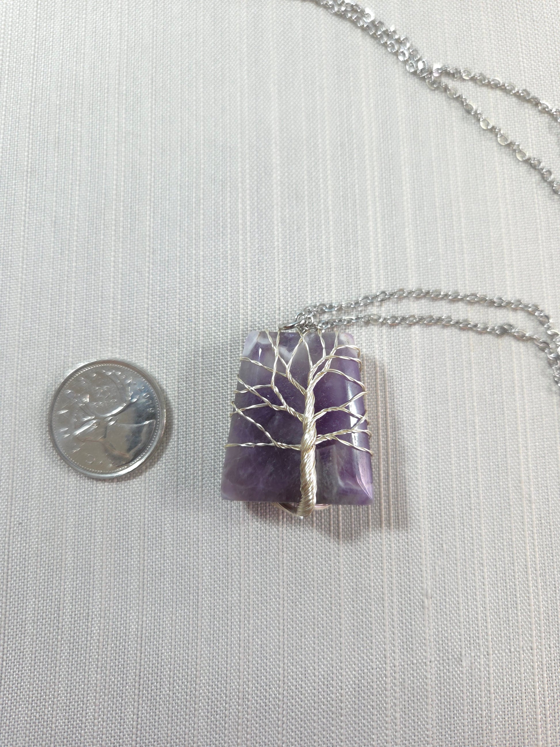Necklace with a purple pendant and silver chain on a white background