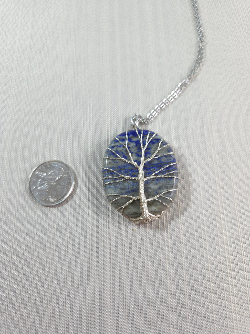 Necklace with a round pendant featuring blue and silver design on a light gray background