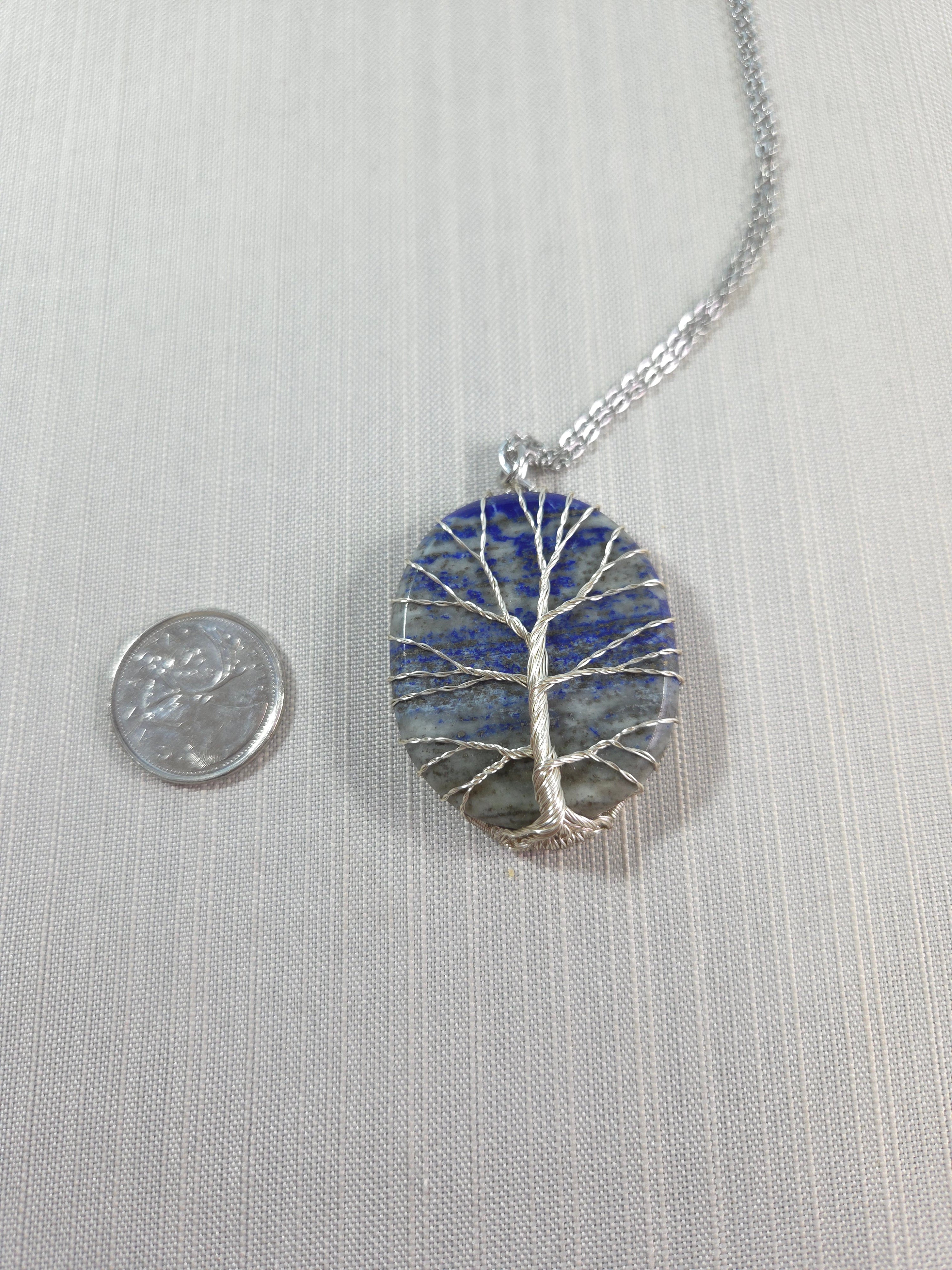 Necklace with a round pendant featuring blue and silver design on a light gray background