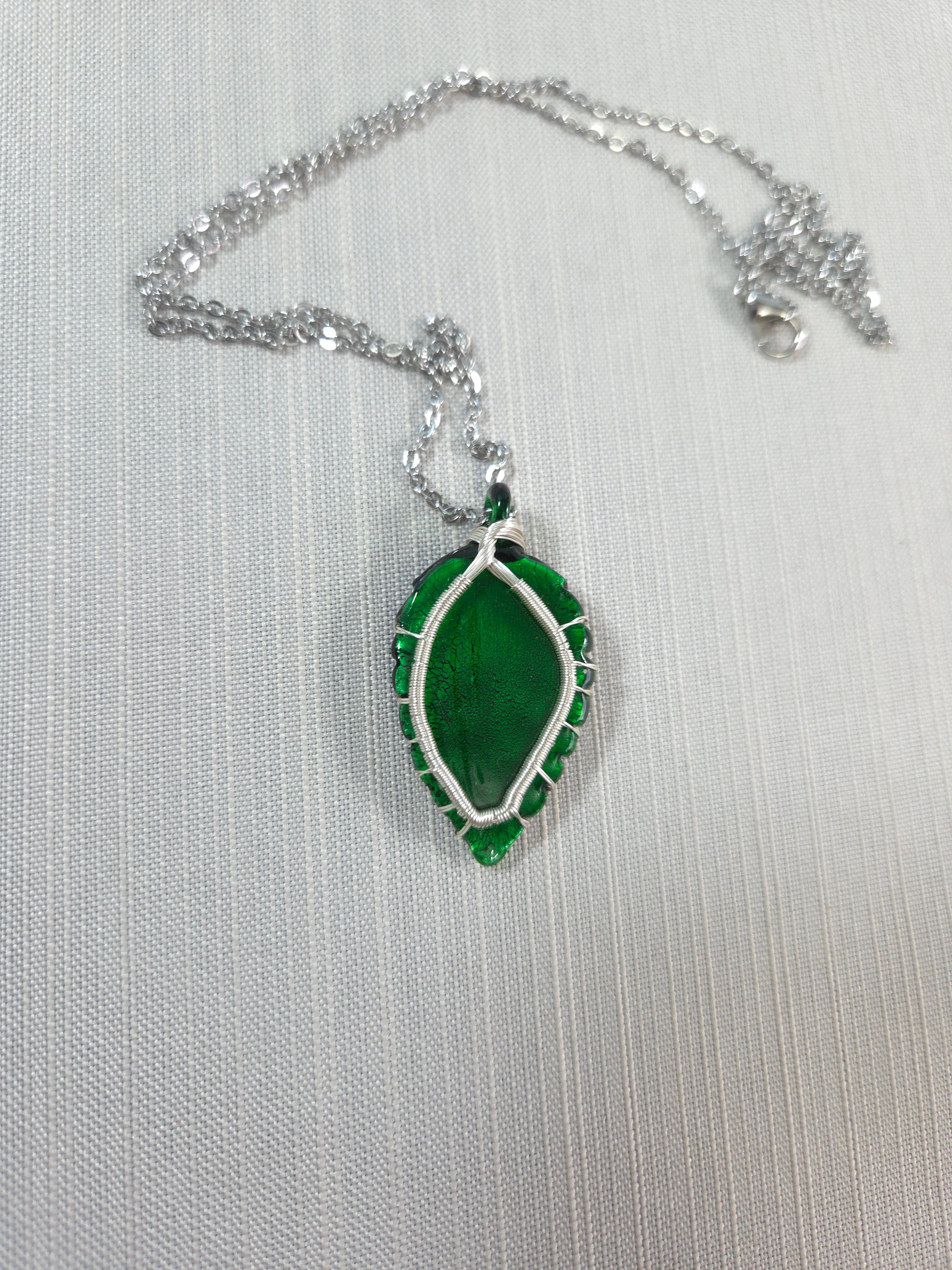 Green leaf-shaped pendant on a silver chain against a white background