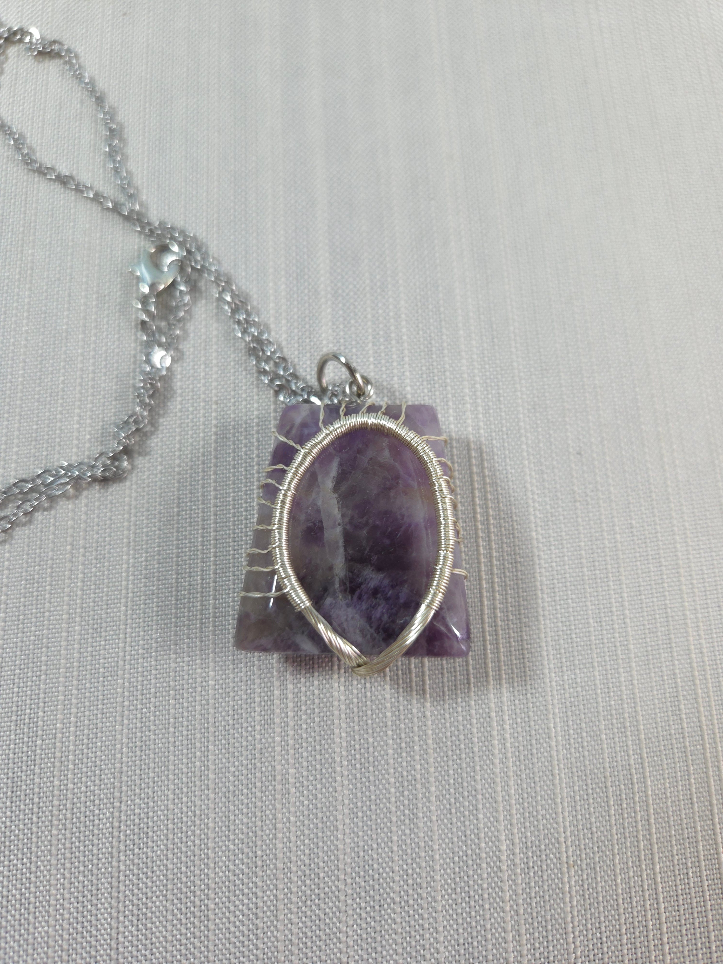 Amethyst pendant with silver chain on a light gray background