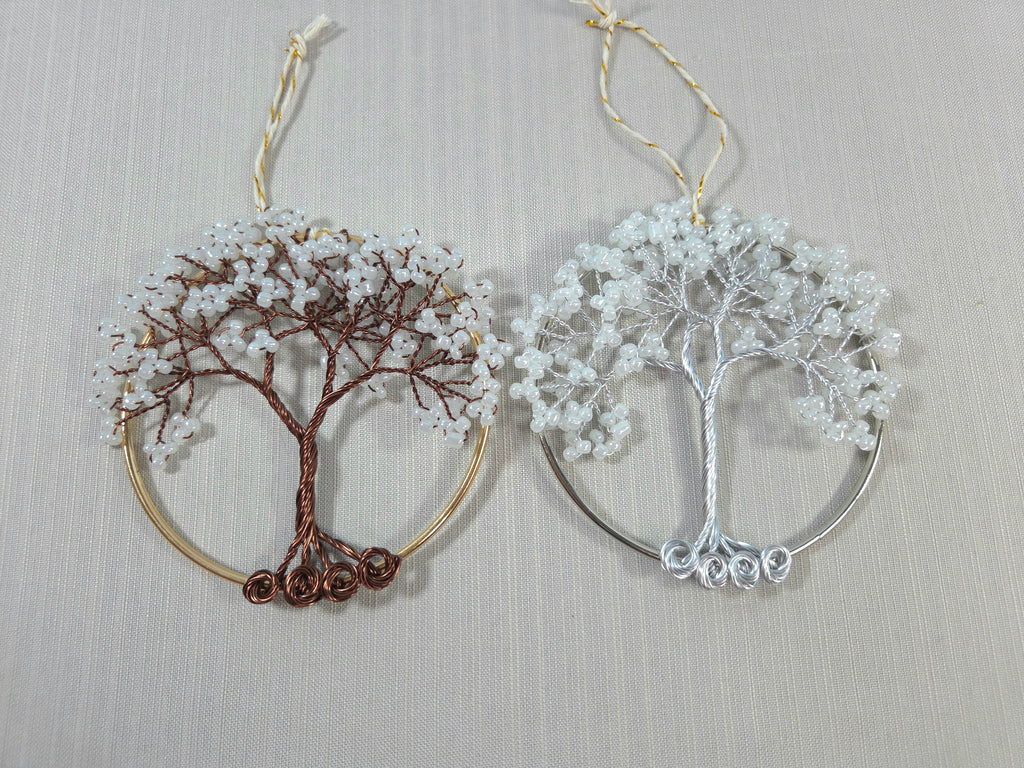 Two tree-shaped earrings, one gold and one silver, on a light gray background.