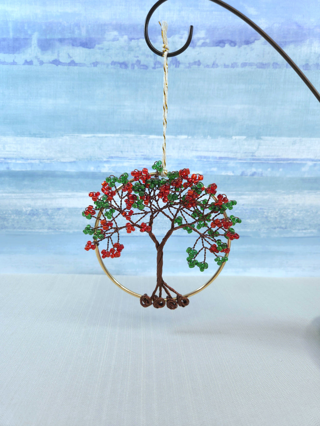 Decorative tree ornament with red berries and green leaves on a blue and white background