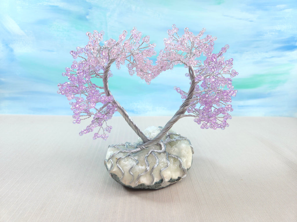 Decorative heart-shaped tree with pink branches on a white base against a blue sky background