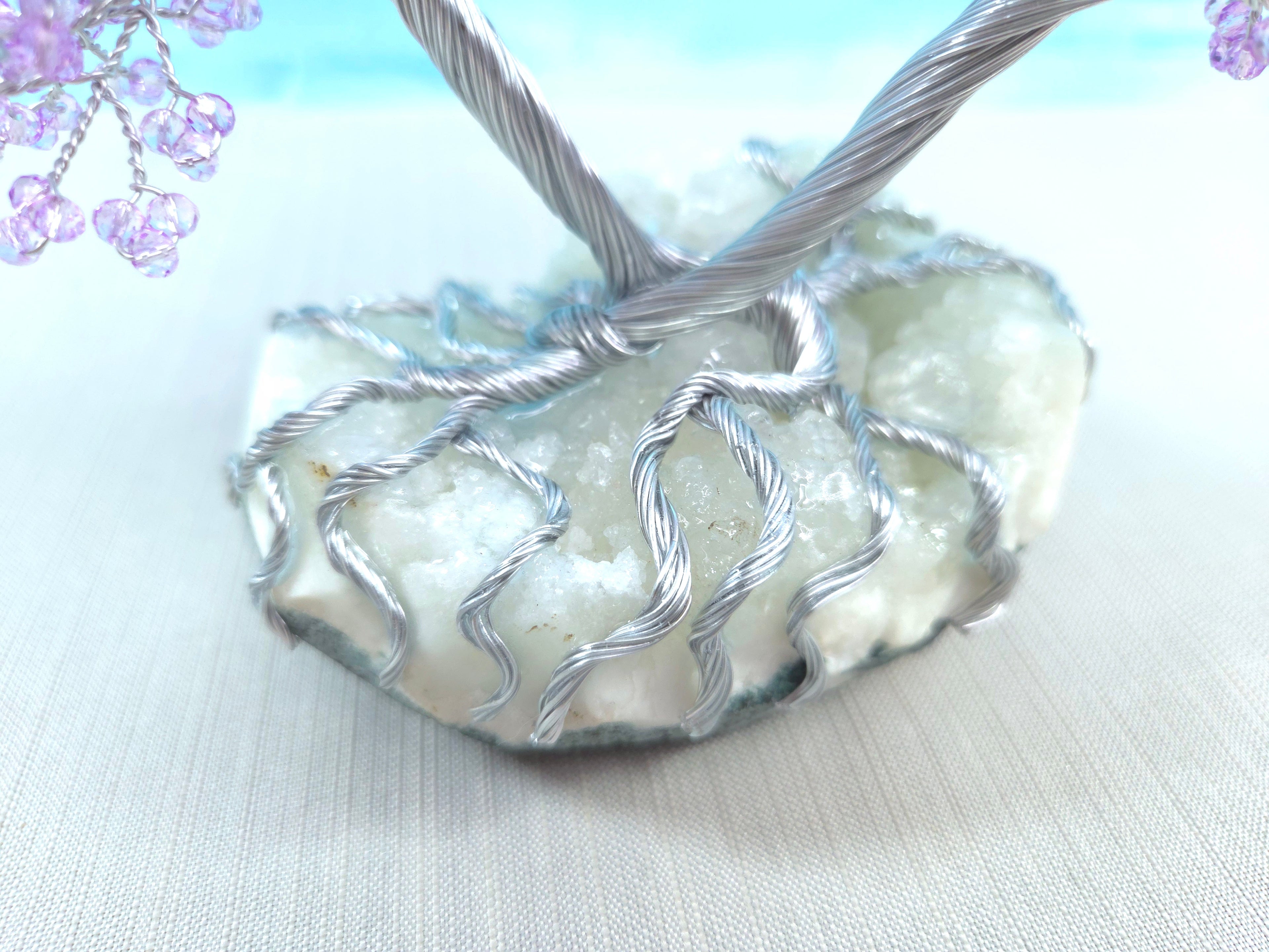Wire-wrapped stone pendant on a light background with floral elements