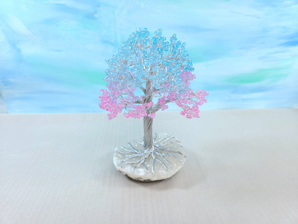 Decorative tree with pink blossoms on a white surface with a blue gradient background