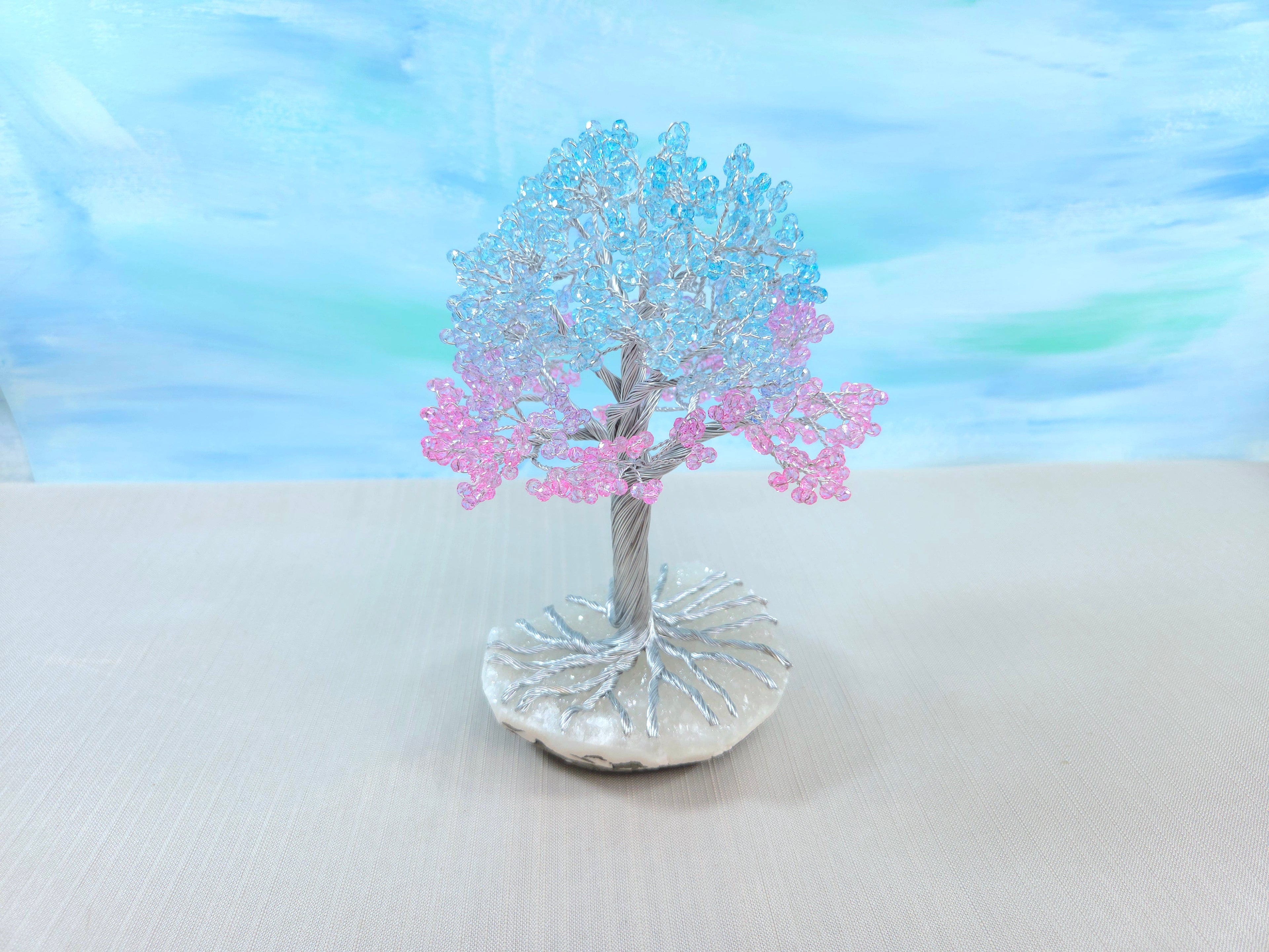Decorative tree with pink blossoms on a white surface with a blue gradient background
