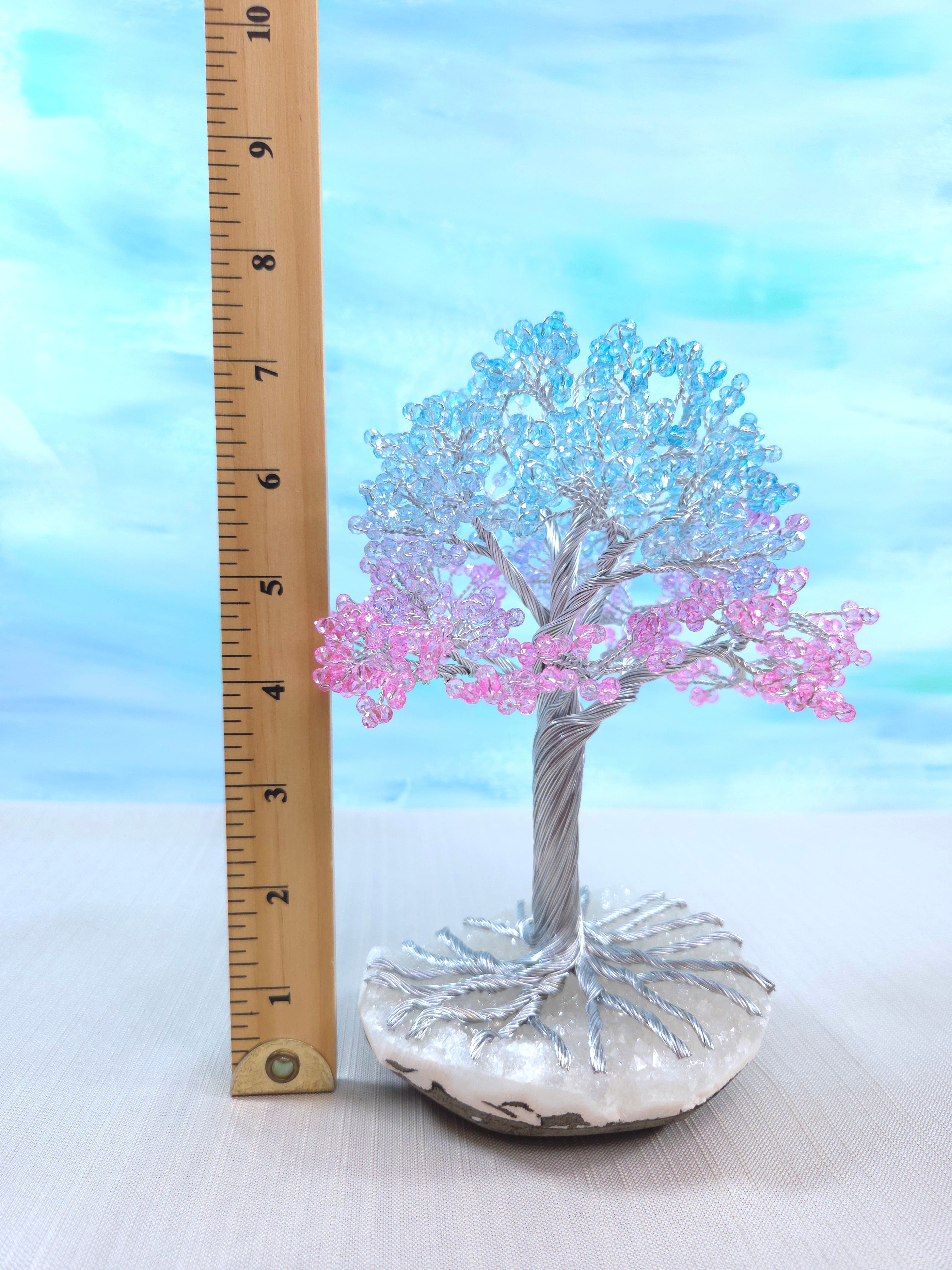 Decorative tree with pink and blue beads next to a ruler for scale on a light background