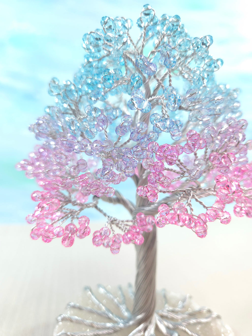Decorative tree made of pink and blue beads against a light blue background